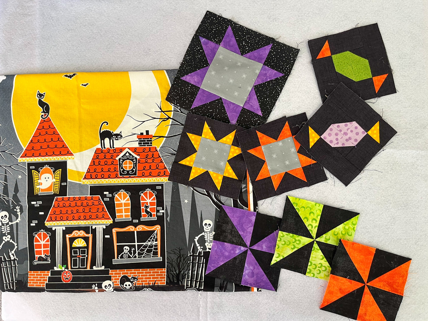 The Creative Spark Quilt Panel Adventure: Design a Legendary Layout features a spooky house and colorful star and pinwheel quilt blocks on a light background—ideal for custom quilt projects or as a unique panel.