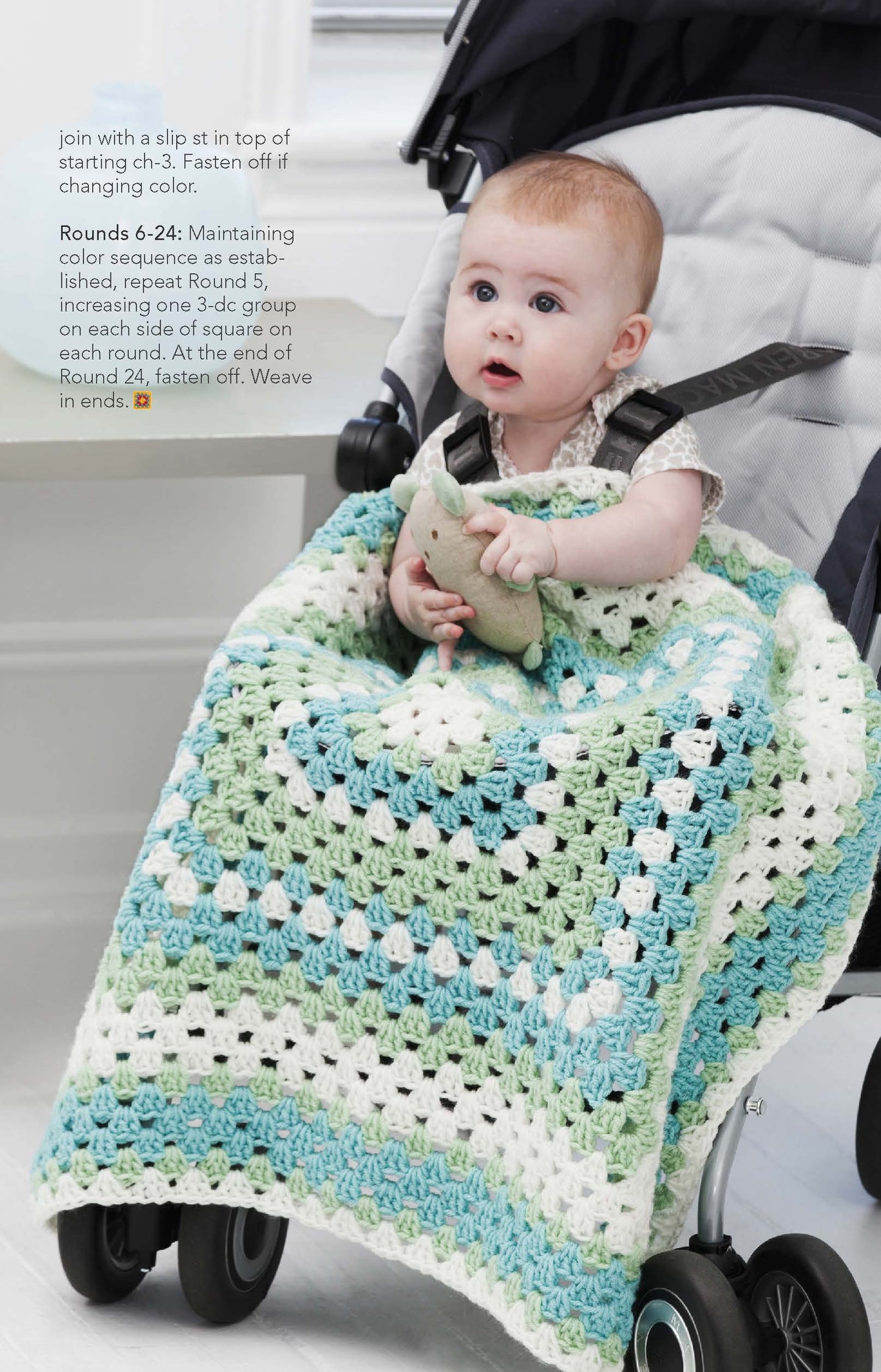 A baby sits in a stroller with a soft toy, covered by a blue, green, and white crocheted blanket made from Leisure Arts' "You Can Do It Granny Squares"—a great beginner project. Crochet round instructions appear on the image's upper left.