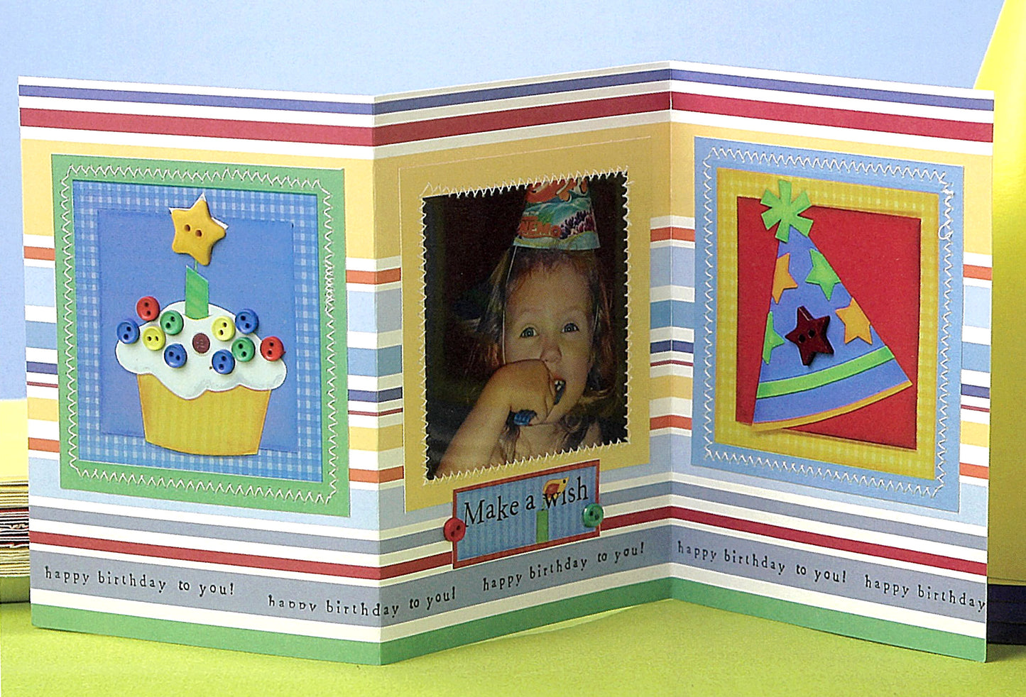 A colorful, tri-fold birthday card from Leisure Arts’ The Ultimate Paper Crafts Collection shows a cupcake, happy child with “Make a wish” caption, party hat, striped borders, and “happy birthday to you!”—perfect for paper crafts fans.