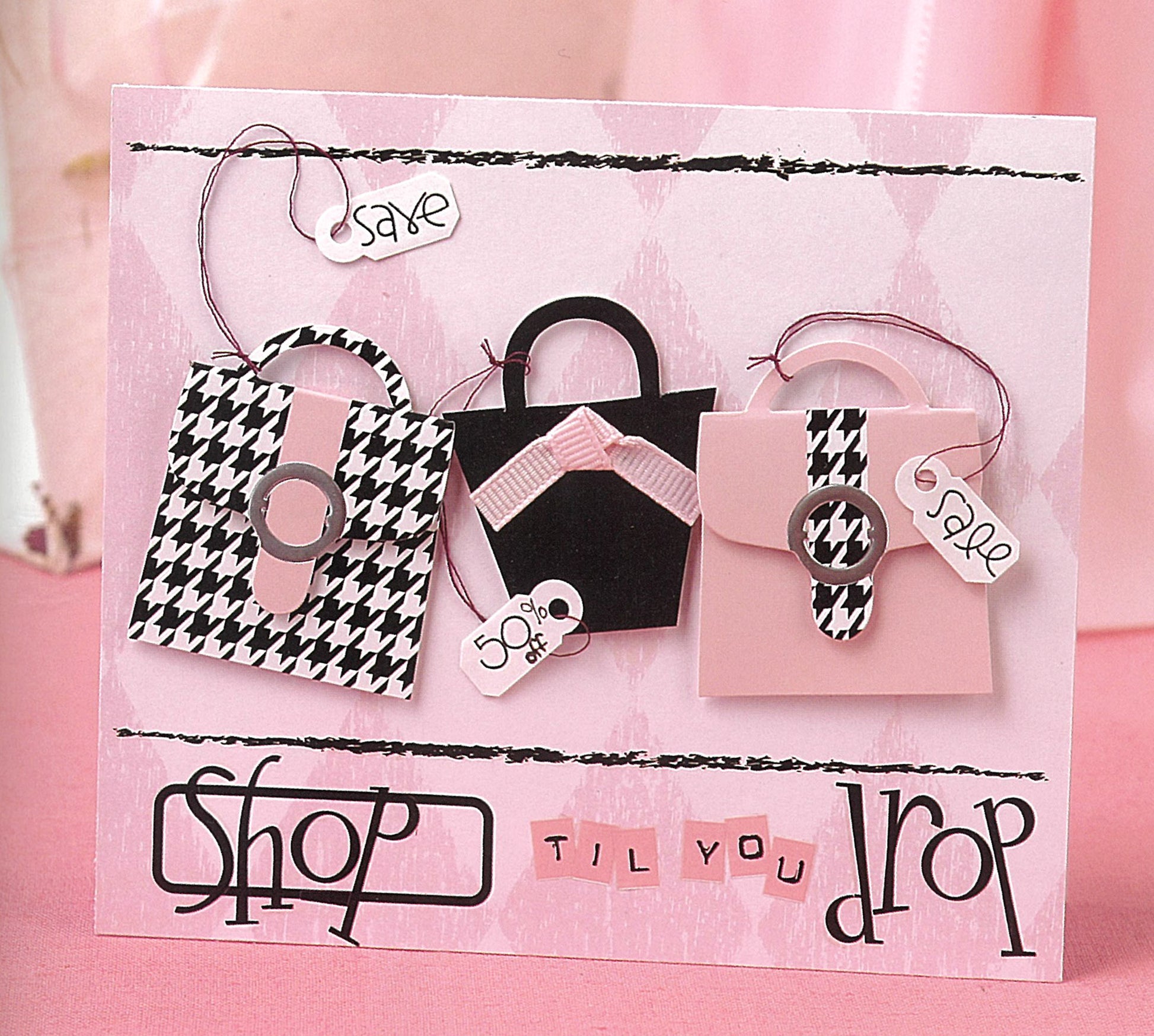 Part of The Ultimate Paper Crafts Collection by Leisure Arts, this greeting card features three illustrated handbags—some in pink and houndstooth—with “save” and “sale” tags, plus “shop til you drop” in playful lettering.
