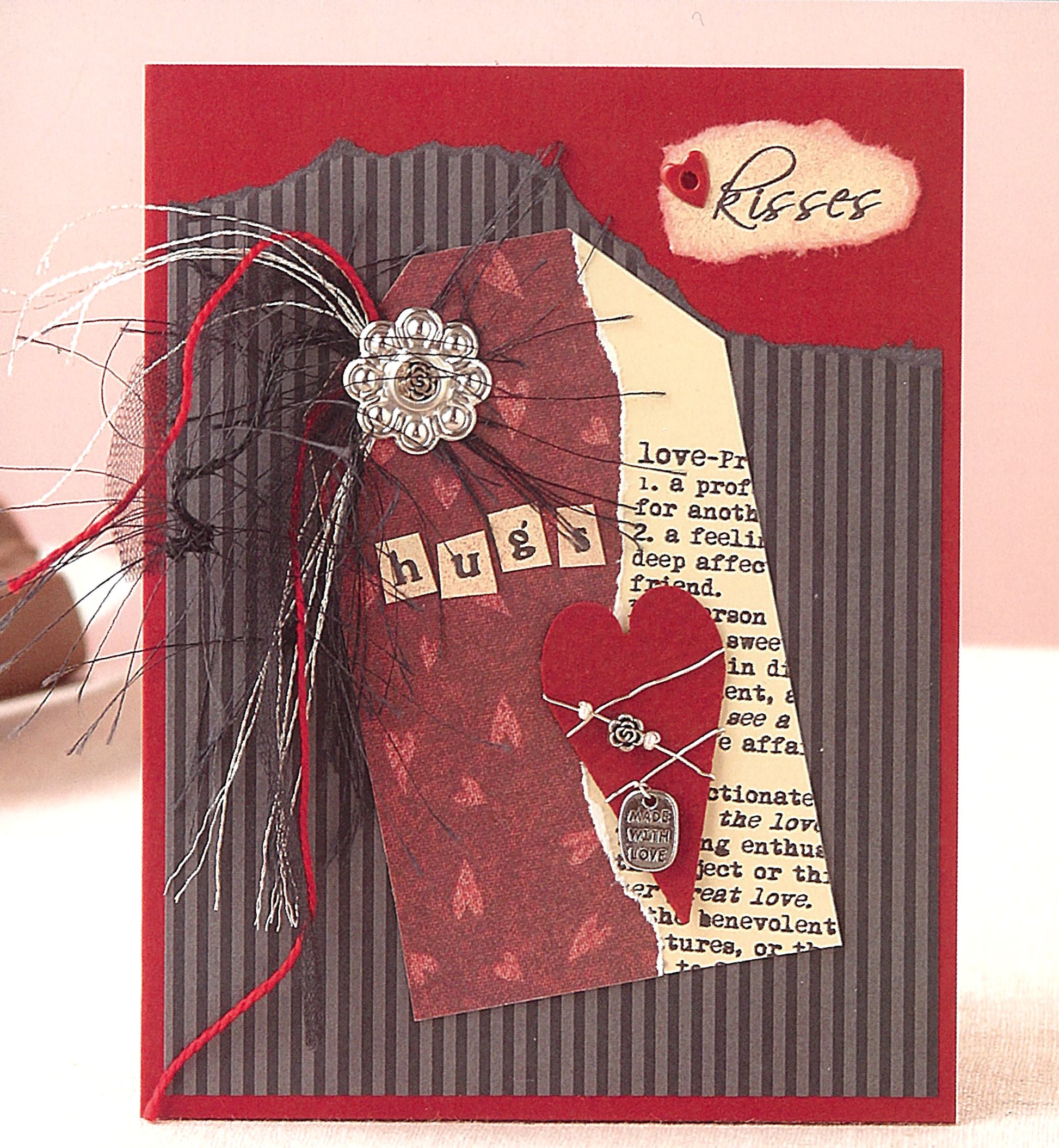 A handmade card from The Ultimate Paper Crafts Collection by Leisure Arts features a red and black striped background, layered papers, a heart, silver flower embellishment, “hugs,” and a “kisses” tag—a true paper crafts treasure.