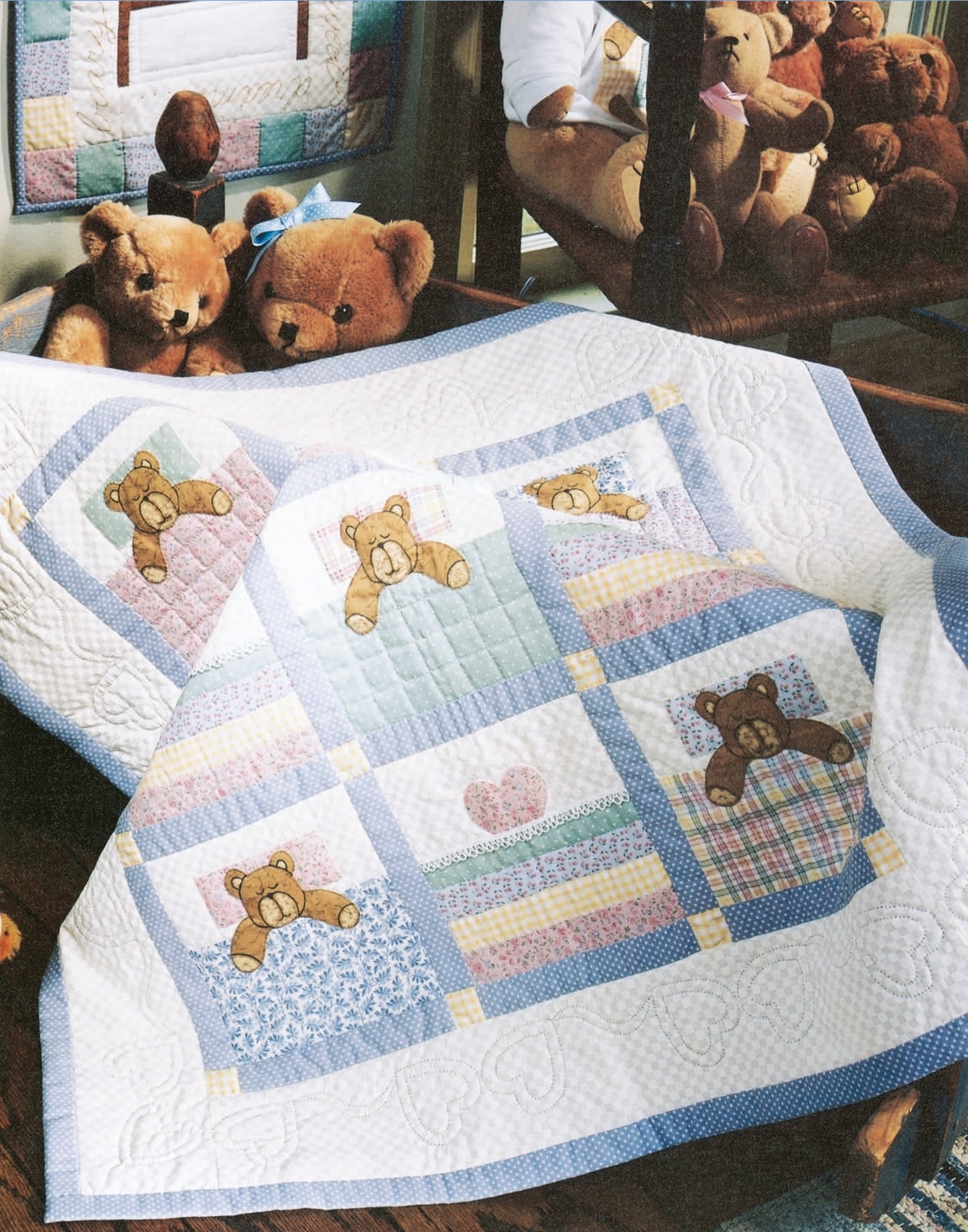 The Rock-a-Bye Quilts by Leisure Arts features a colorful patchwork baby quilt with teddy bear designs and heart motifs, creating a soft, cozy nursery atmosphere—perfect for draping over a crib and surrounding with plush teddy bears.