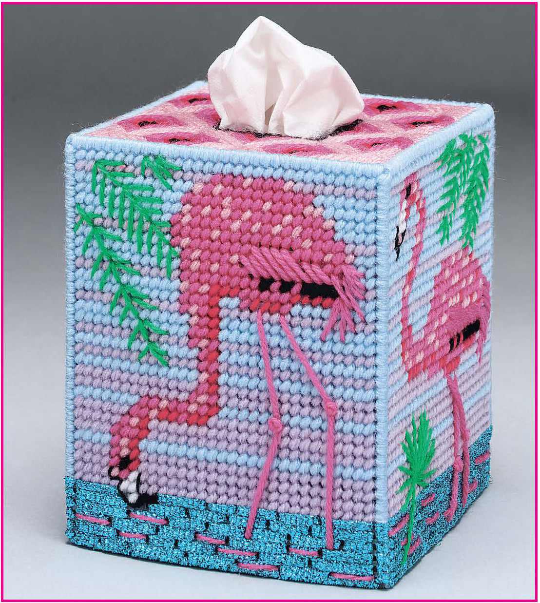 The Room by Room Plastic Canvas Tissue Box Covers Digital Download from Leisure Arts features a beginner-friendly flamingo pattern with green leaves and blue water, using pink, blue, and purple yarn—a perfect craft for plastic canvas fans.