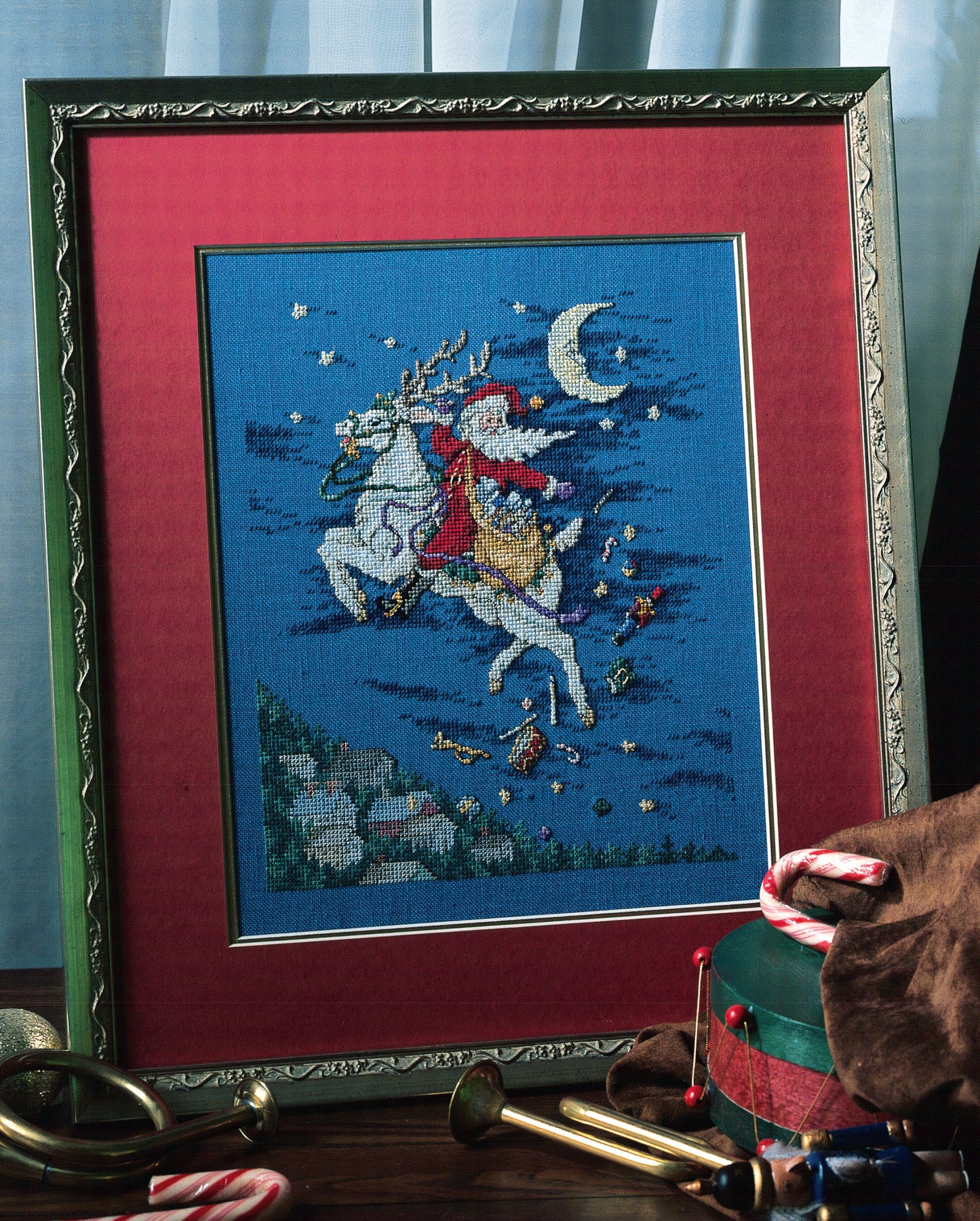 Leisure Arts' "Santa's Great Book of Cross Stitch" features festive patterns like Santa riding a white reindeer in a starry night sky, with candy canes and holiday toys—perfect for fans of Christmas cross stitch.