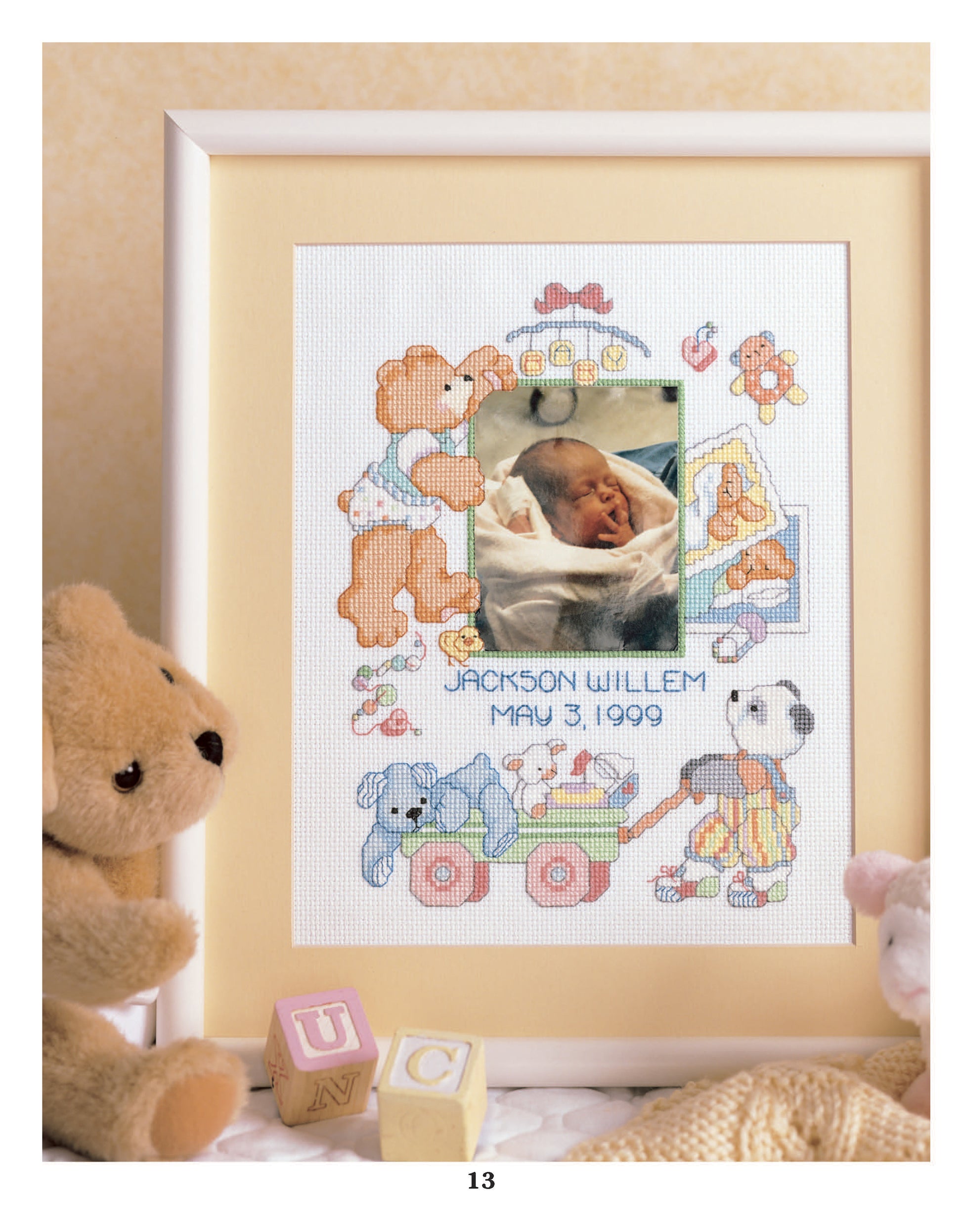 The Sweet Baby Cross Stitch Memories by Leisure Arts features a framed birth announcement with a newborn’s photo, surrounded by charming cross stitch designs of teddy bears, blocks, and toys—an adorable keepsake for any baby.