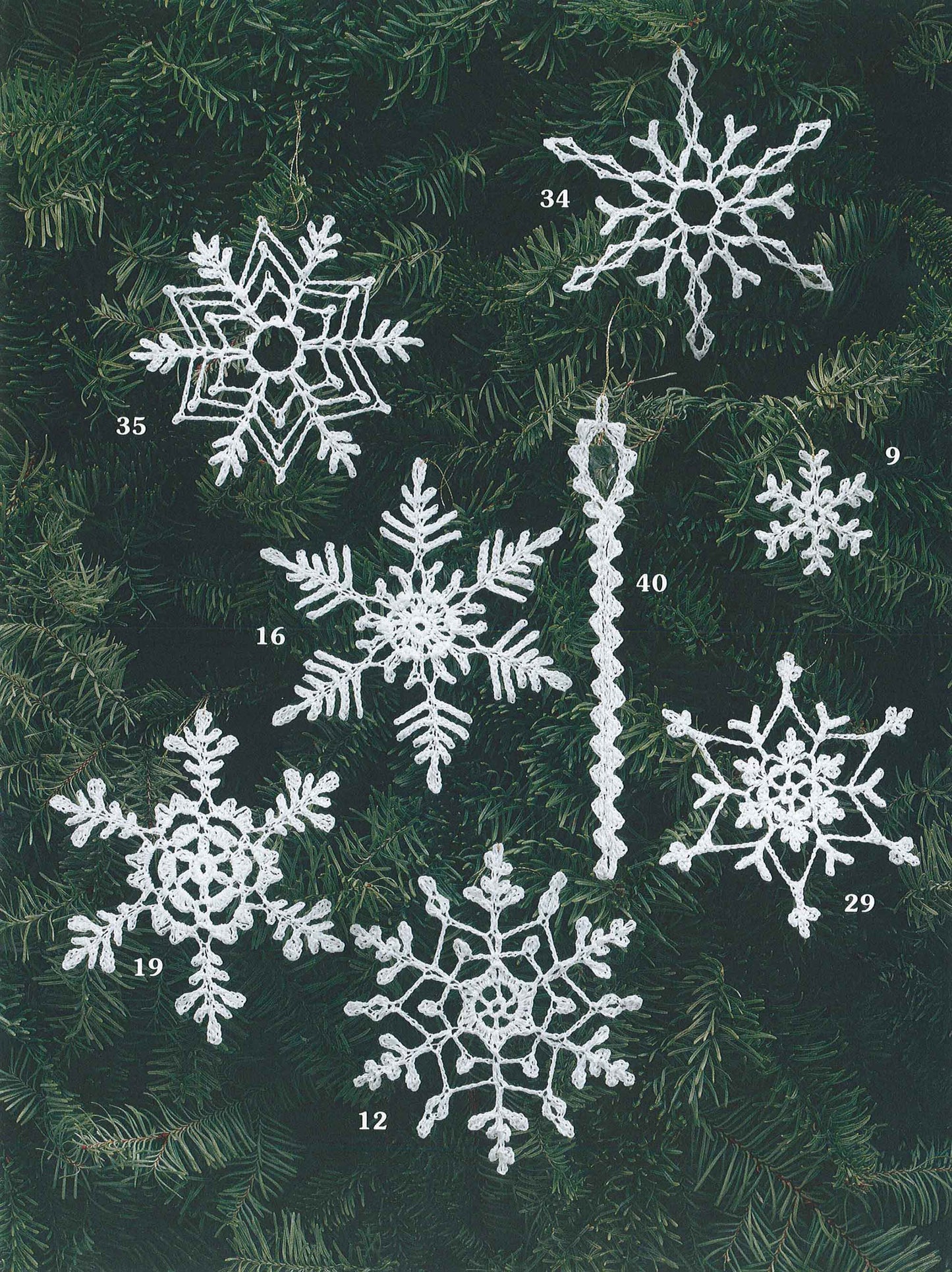 Eight unique crocheted snowflake and icicle ornaments from "White Christmas in Thread Crochet" by Leisure Arts are displayed on pine branches, perfect as festive decorations or to enhance your holiday garlands.