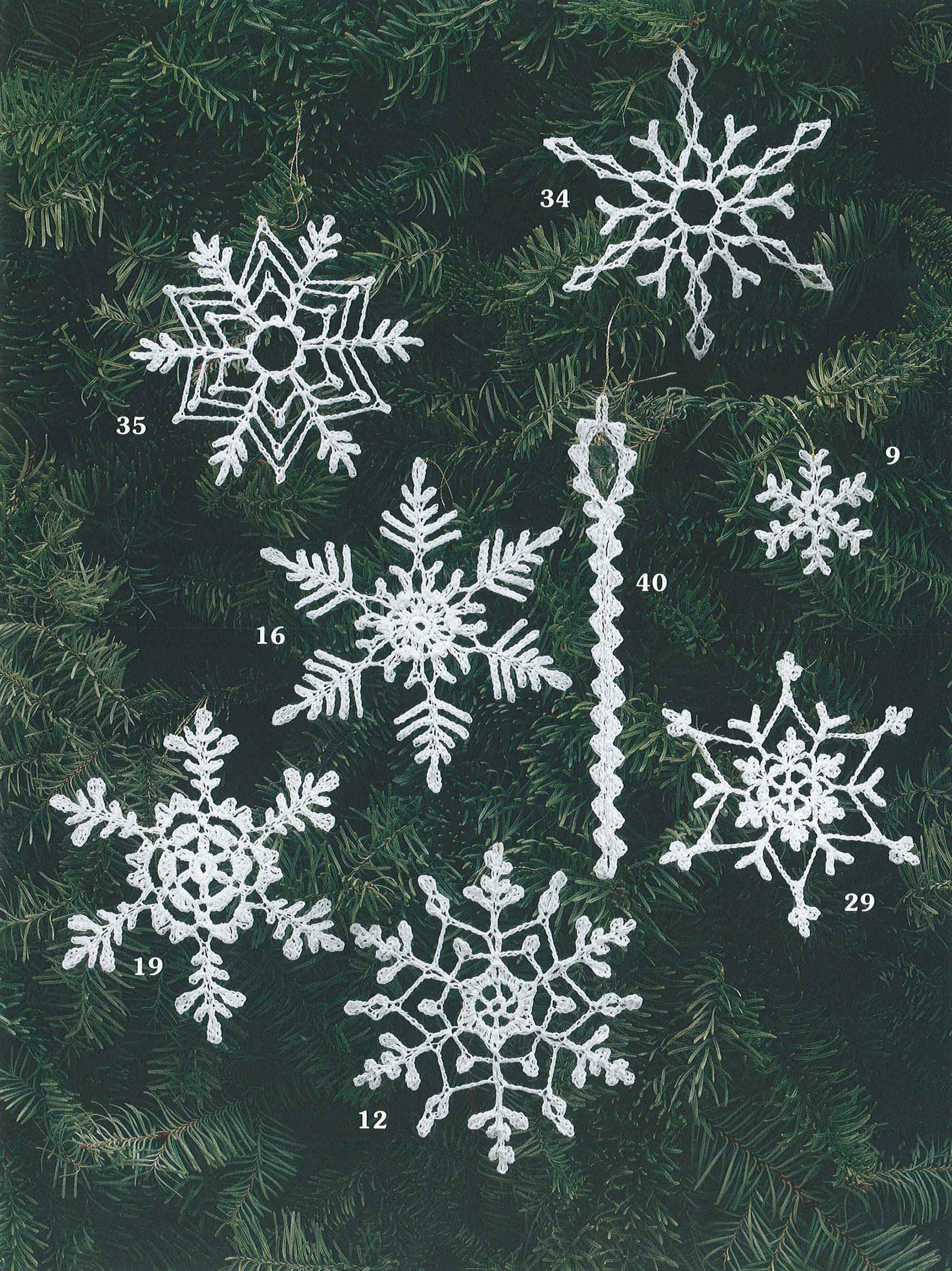 Eight unique crocheted snowflake and icicle ornaments from "White Christmas in Thread Crochet" by Leisure Arts are displayed on pine branches, perfect as festive decorations or to enhance your holiday garlands.