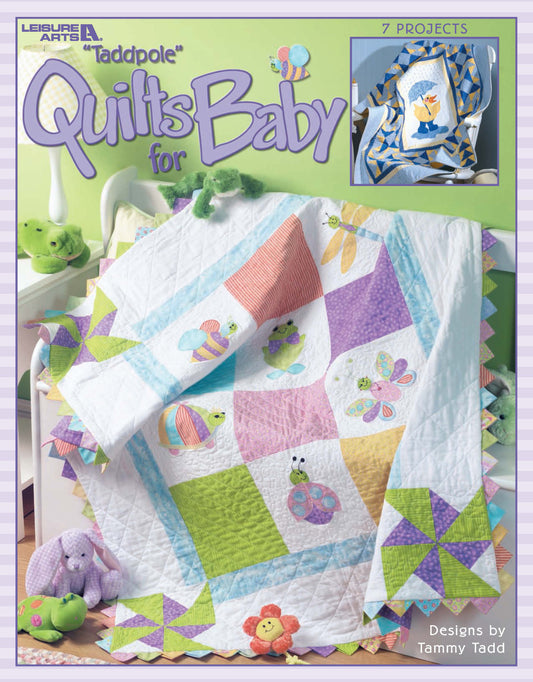 A colorful baby quilt with appliqué turtles, butterflies, and flowers drapes over a crib rail. The cover reads "Tadpole Quilts for Baby" by Leisure Arts, featuring seven easy quilt patterns with simple-to-piece blocks.