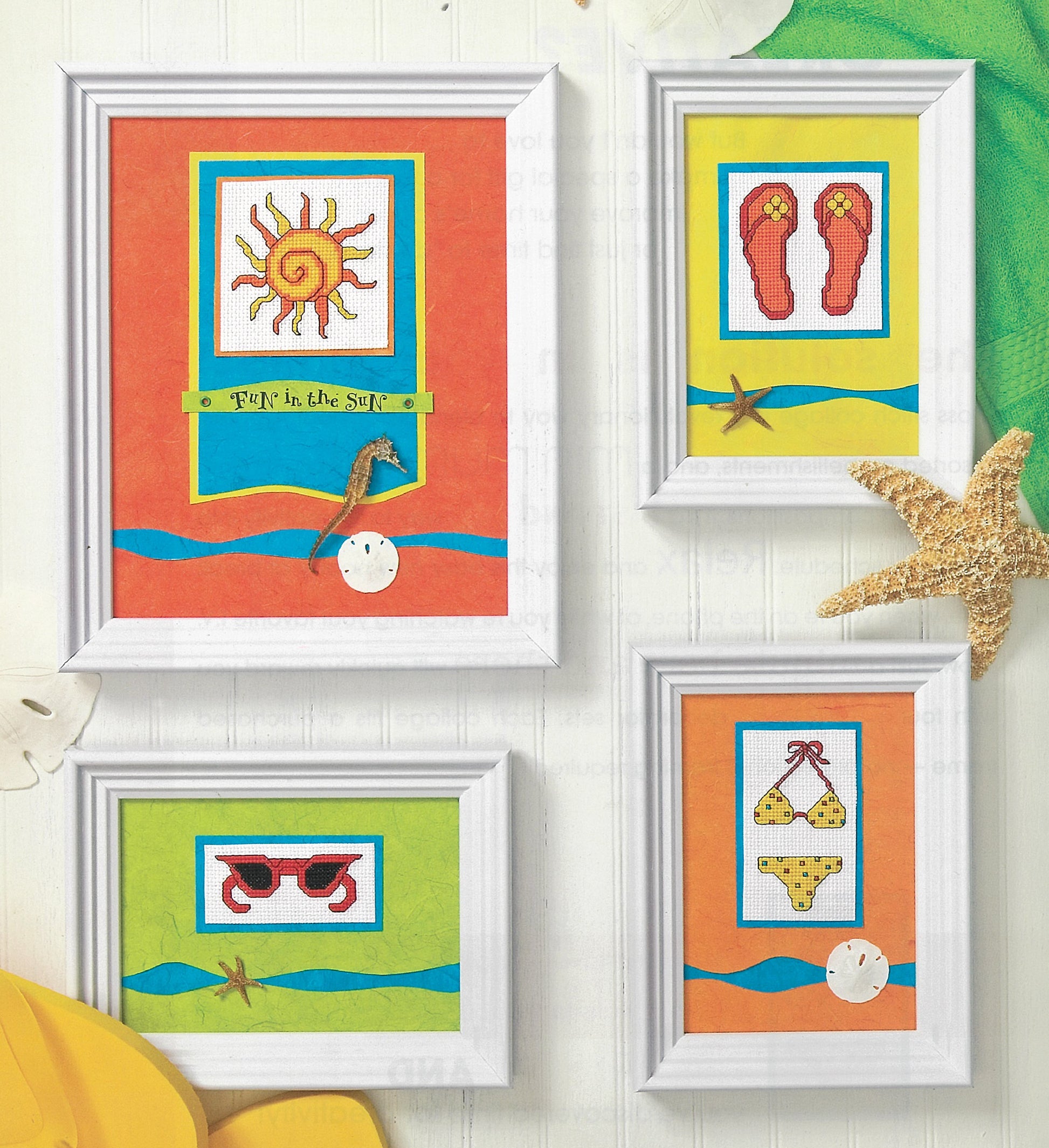 Four white-framed pictures with summer-themed art—featured in Leisure Arts’ Quick & Easy Decorating—are displayed on colorful scrapbook paper with red flip-flops, sunglasses, a yellow bikini, and a starfish beside the frames.