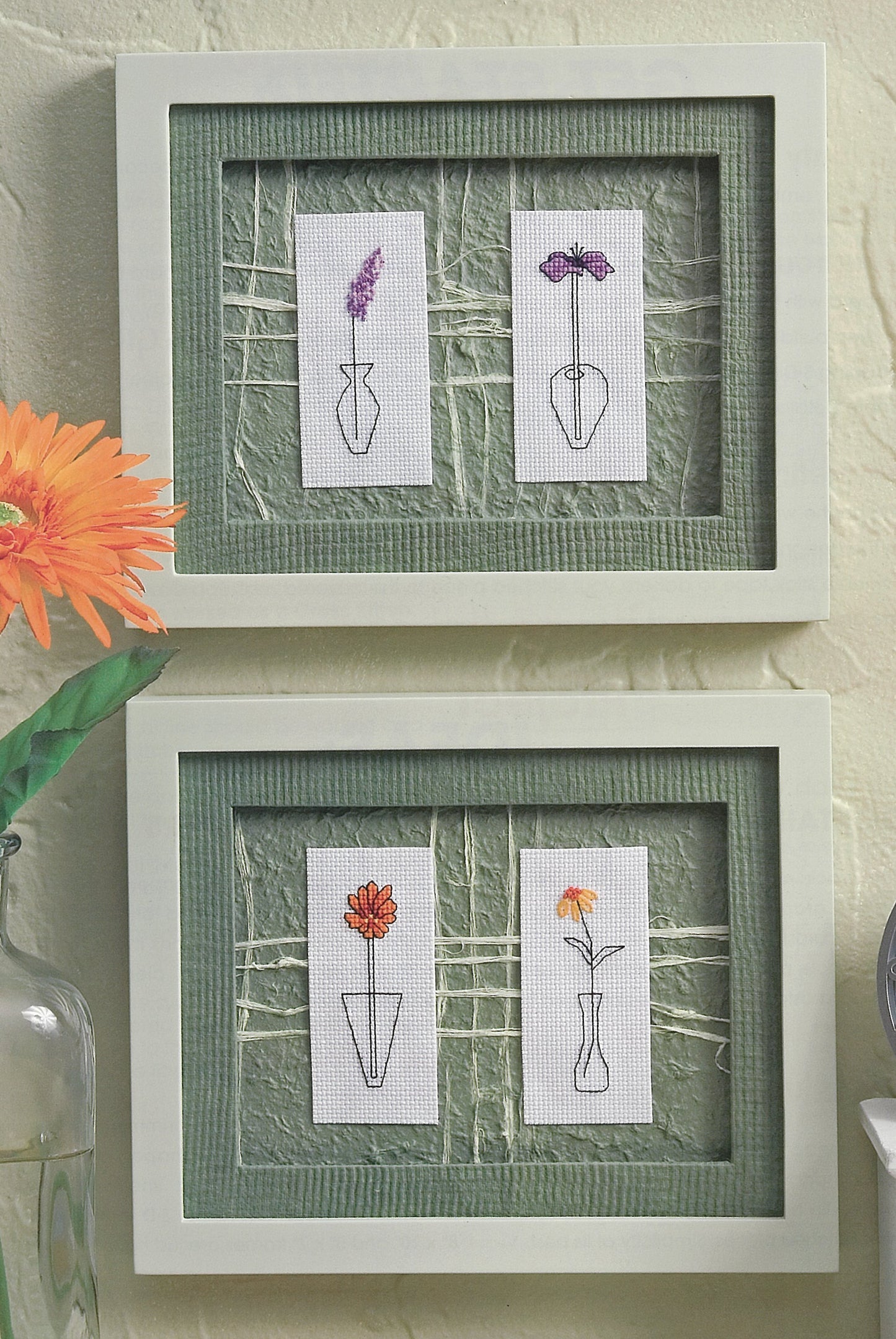 Quick & Easy Decorating by Leisure Arts features two framed artworks with minimalist embroidered vases and flowers on green and white backgrounds. Two blooms appear in the top frame, different florals below, all accented by a bright orange flower.