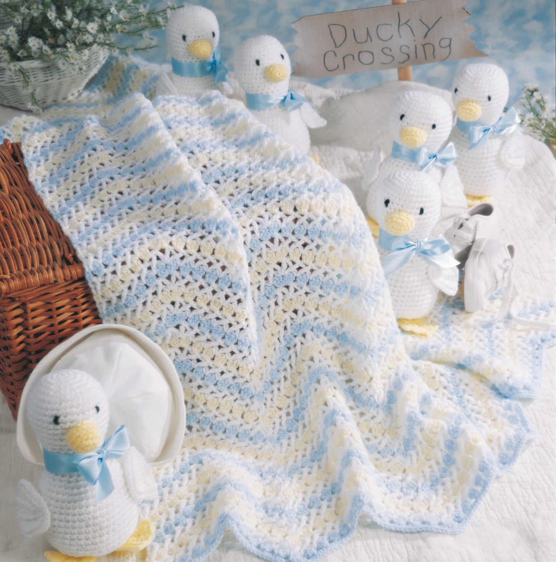 The Just Ducky Baby Afghans Digital Download by Leisure Arts features a crocheted baby blanket with pastel stripes, surrounded by duck toys, a basket, bonnet, and Ducky Crossing sign—ideal for nursery gifts or Leisure Arts fans.