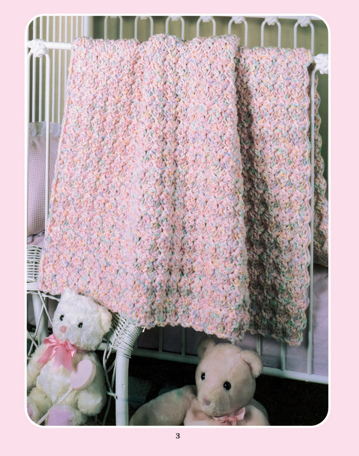 A cozy nursery features a pastel crochet baby blanket made with worsted weight yarn using the "More Double-Quick for Baby Digital Download" pattern by Leisure Arts, draped over a white crib rail with two stuffed bears nearby.