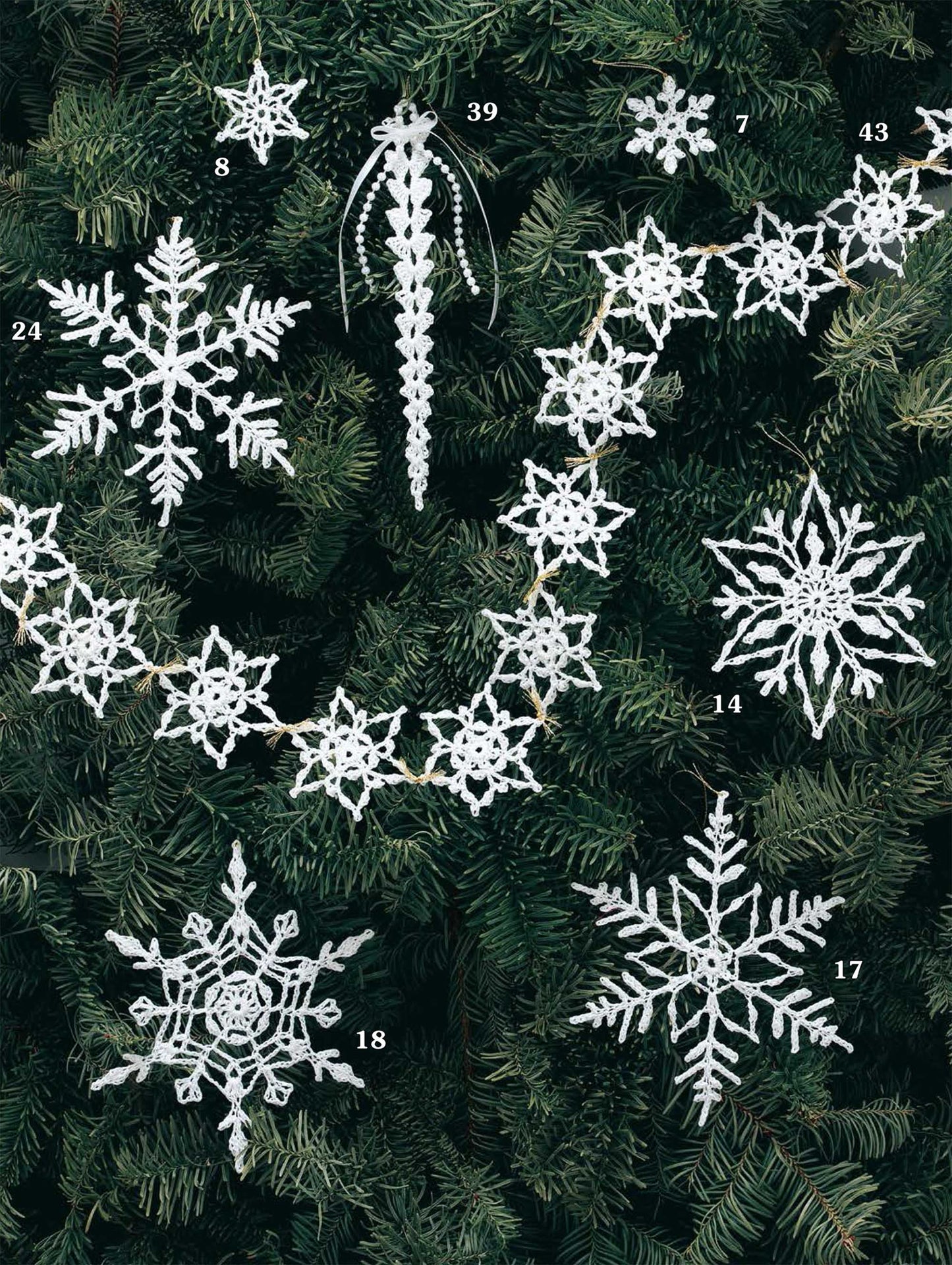 Leisure Arts' "White Christmas in Thread Crochet" digital download features white crocheted snowflake and icicle ornaments, each numbered, displayed on a green pine tree for festive holiday decor.