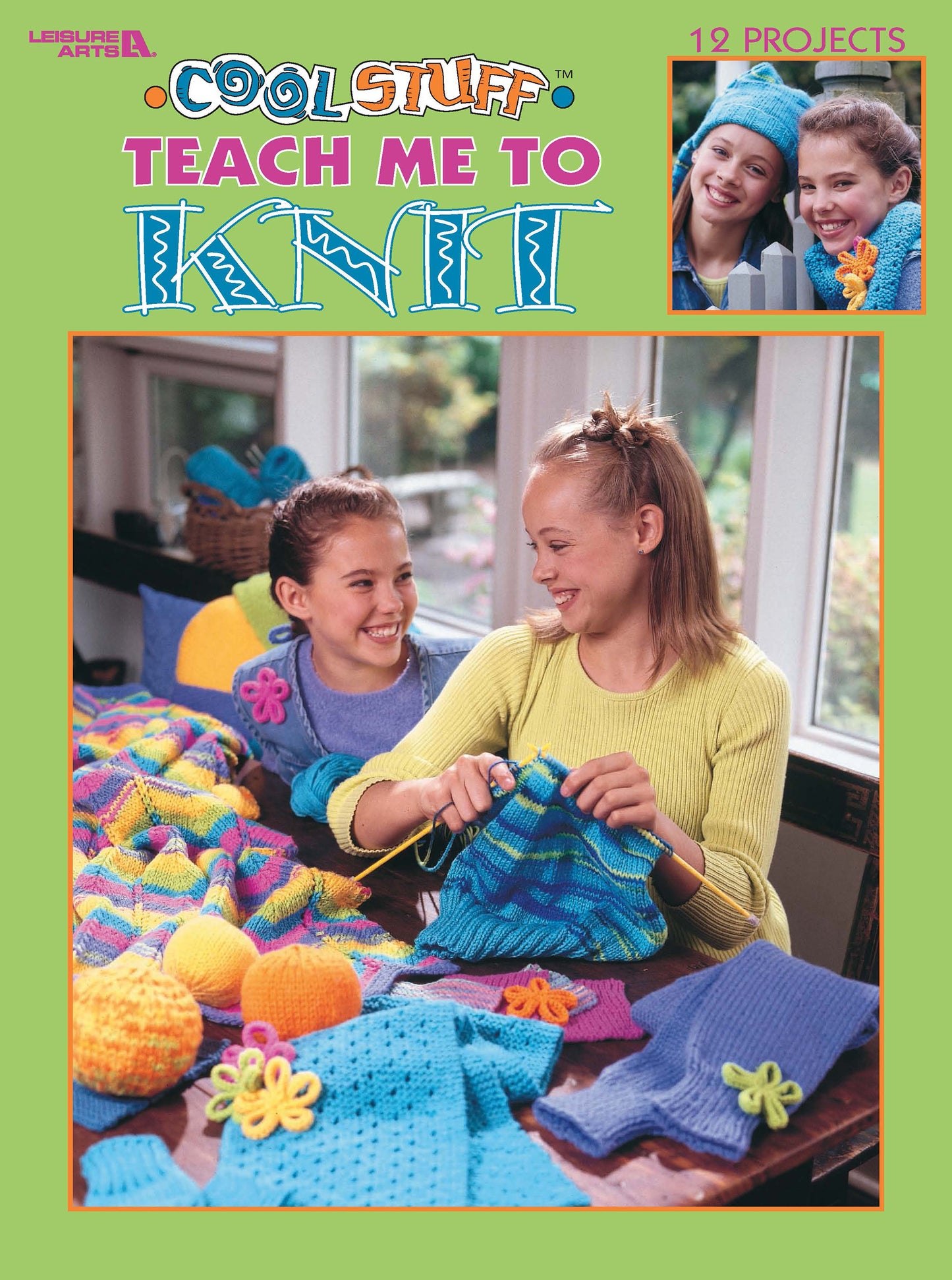 Two smiling girls sit at a table covered in colorful knitting projects. One holds blue yarn and needles. The cover reads "Cool Stuff for Kids Teach Me to Knit—12 Projects Digital Download" by Leisure Arts, ideal for beginner knitters.