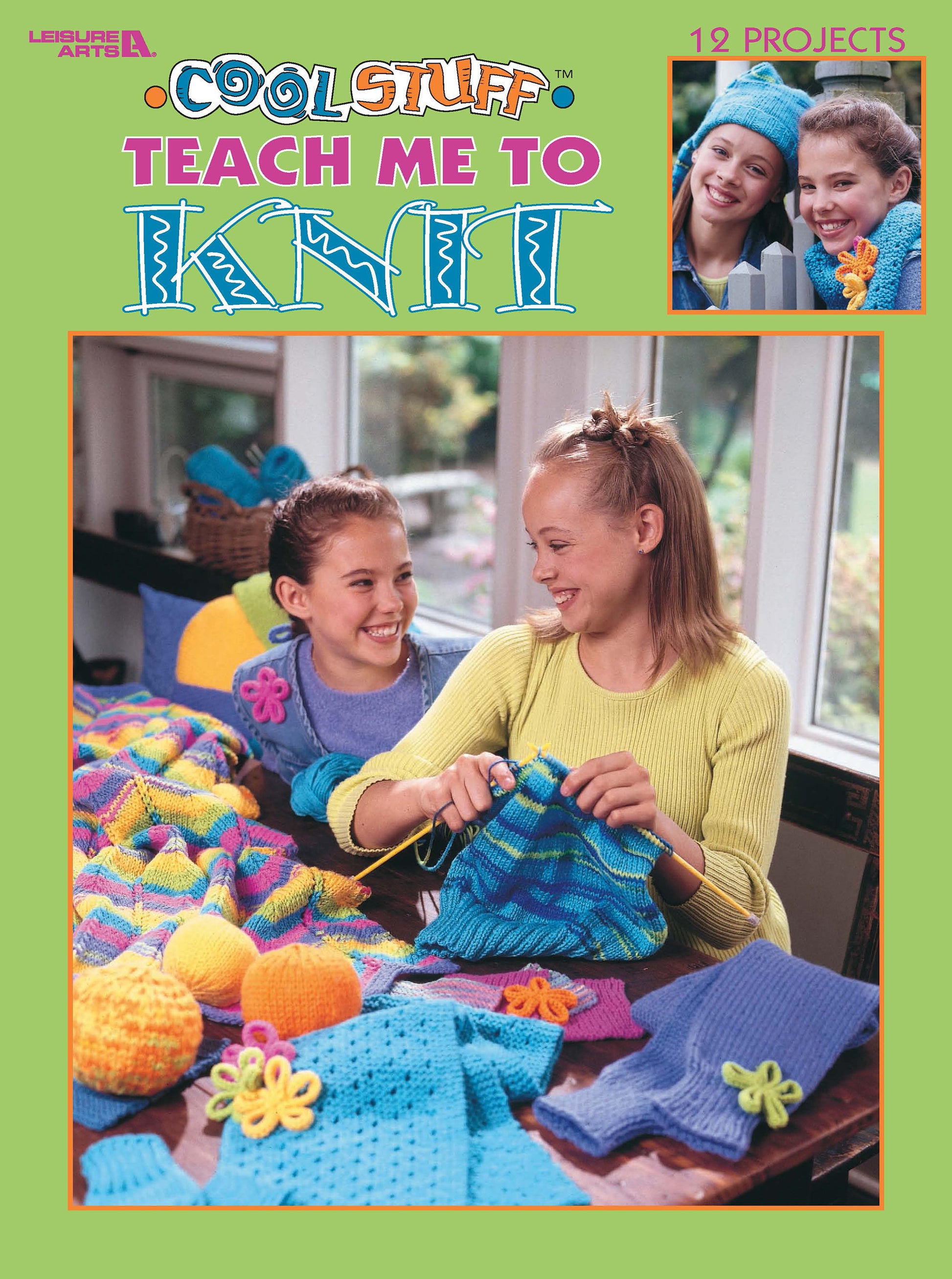 Two smiling girls sit at a table covered in colorful knitting projects. One holds blue yarn and needles. The cover reads "Cool Stuff for Kids Teach Me to Knit—12 Projects Digital Download" by Leisure Arts, ideal for beginner knitters.