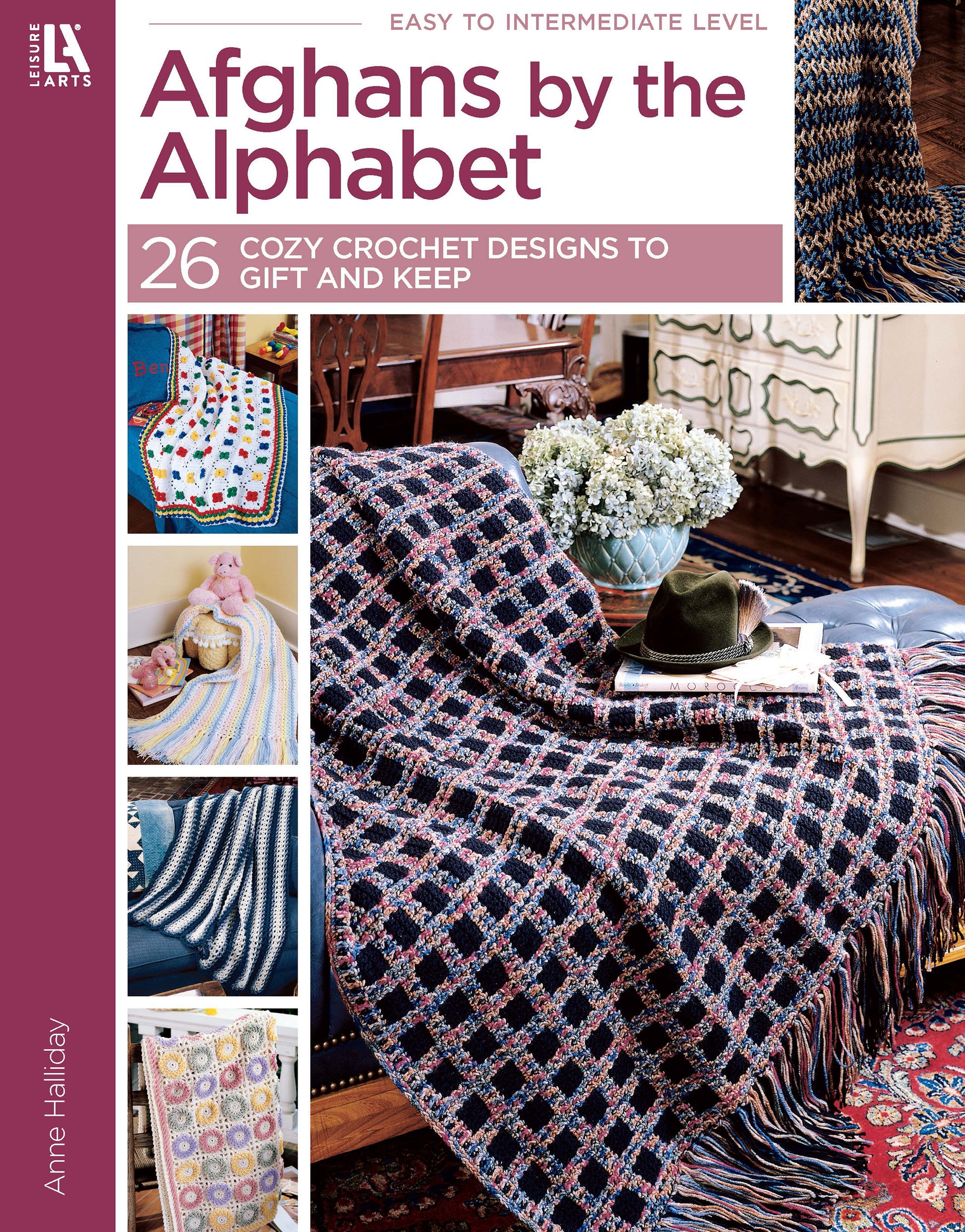Cover of Afghans by the Alphabet Digital Download from Leisure Arts features cozy crochet designs over a chair and sofa, with 26 patterns—including baby blankets—to gift or keep, plus a table with books, flowers, and glasses.
