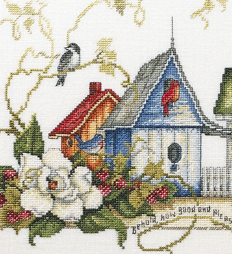The Unity Birdhouses Cross Stitch Digital Download by Leisure Arts features two birdhouses with perched birds, white flowers, green leaves, and red berries on a white background accented with gold stitching.