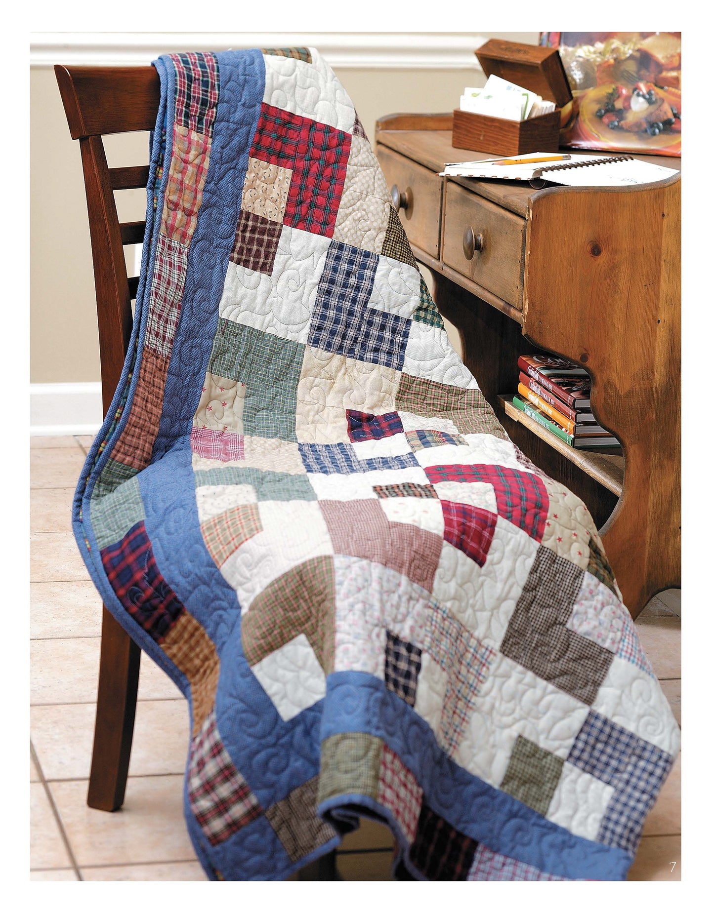 A cozy room features a wooden chair draped with a quilt inspired by Slash Your Stash Quilts Digital Download from Leisure Arts, its vibrant patchwork and fast piecing design brightening the space beside a rustic desk.