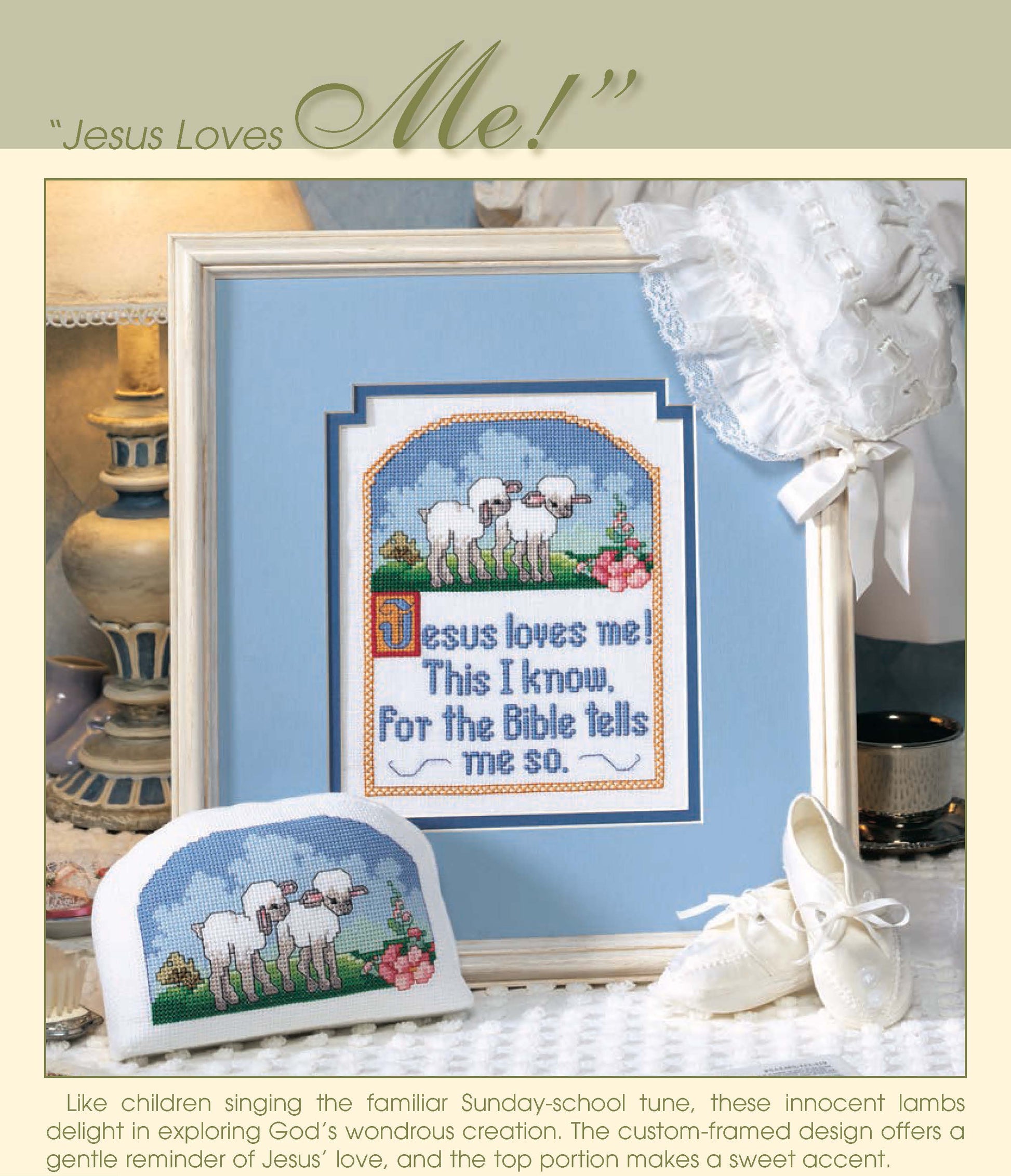 Simply Inspirational by Leisure Arts features a framed cross-stitch on Aida cloth of lambs and “Jesus loves me! This I know, For the Bible tells me so” with a white baby bonnet, shoes, and a matching smaller cross-stitch piece displayed in front.