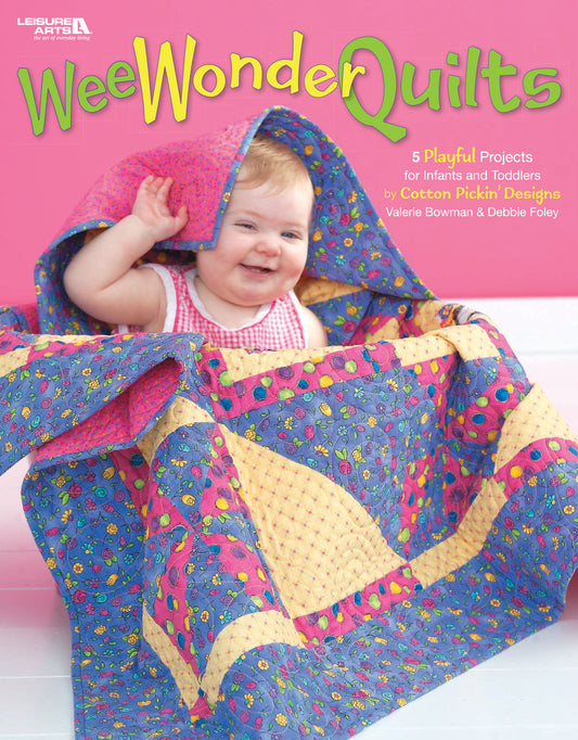 A smiling baby in pink sits under a colorful quilt, highlighting playful patterns. Cover text: Wee Wonder Quilts Digital Download by Leisure Arts—5 playful projects for infants and toddlers.
