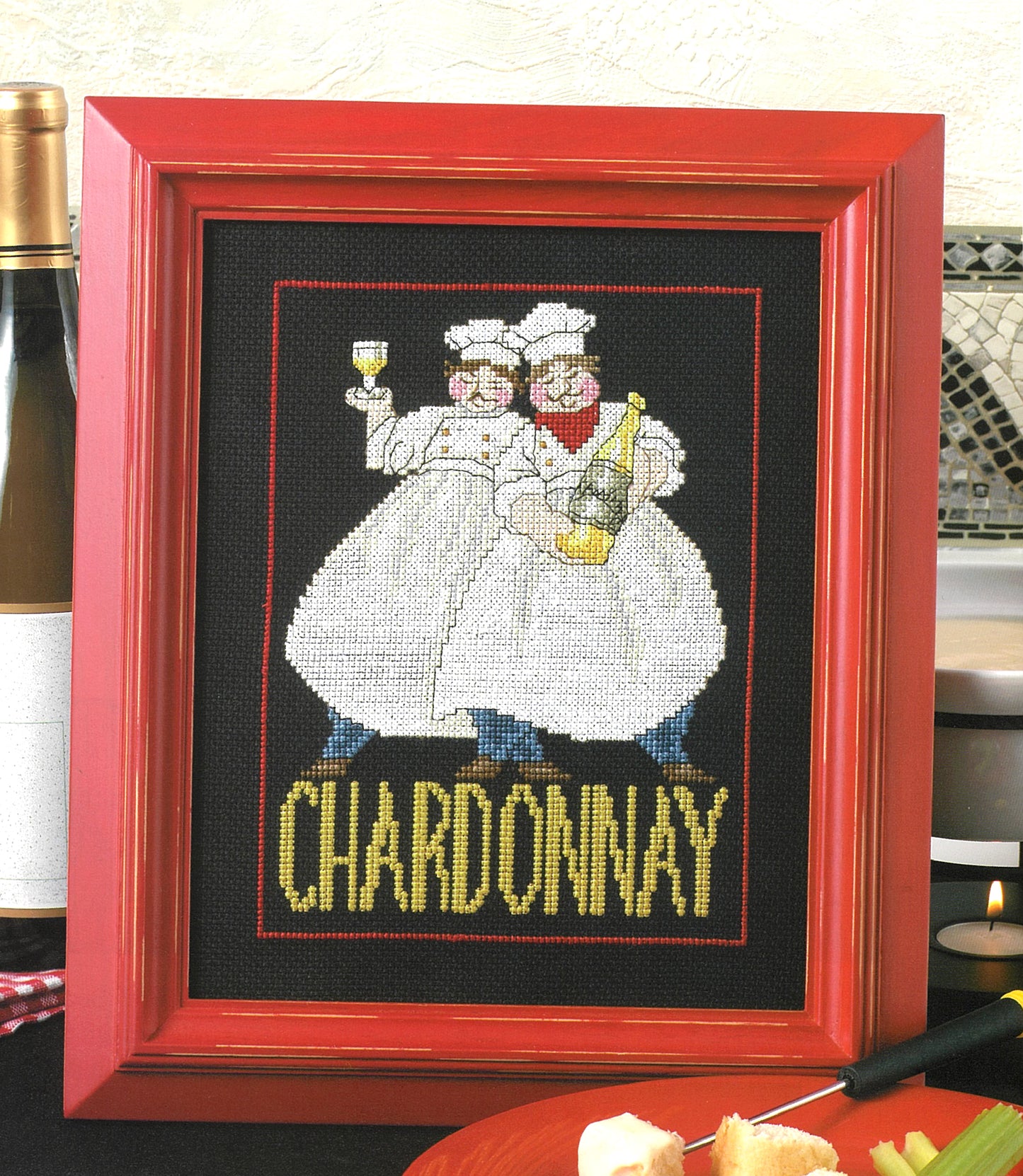 Leisure Arts' "French Chefs—4 Cross Stitch Designs" features chefs in white holding wine, with "CHARDONNAY" stitched below. Framed in bold red, this stylish kitchen decor makes a charming addition to any space.