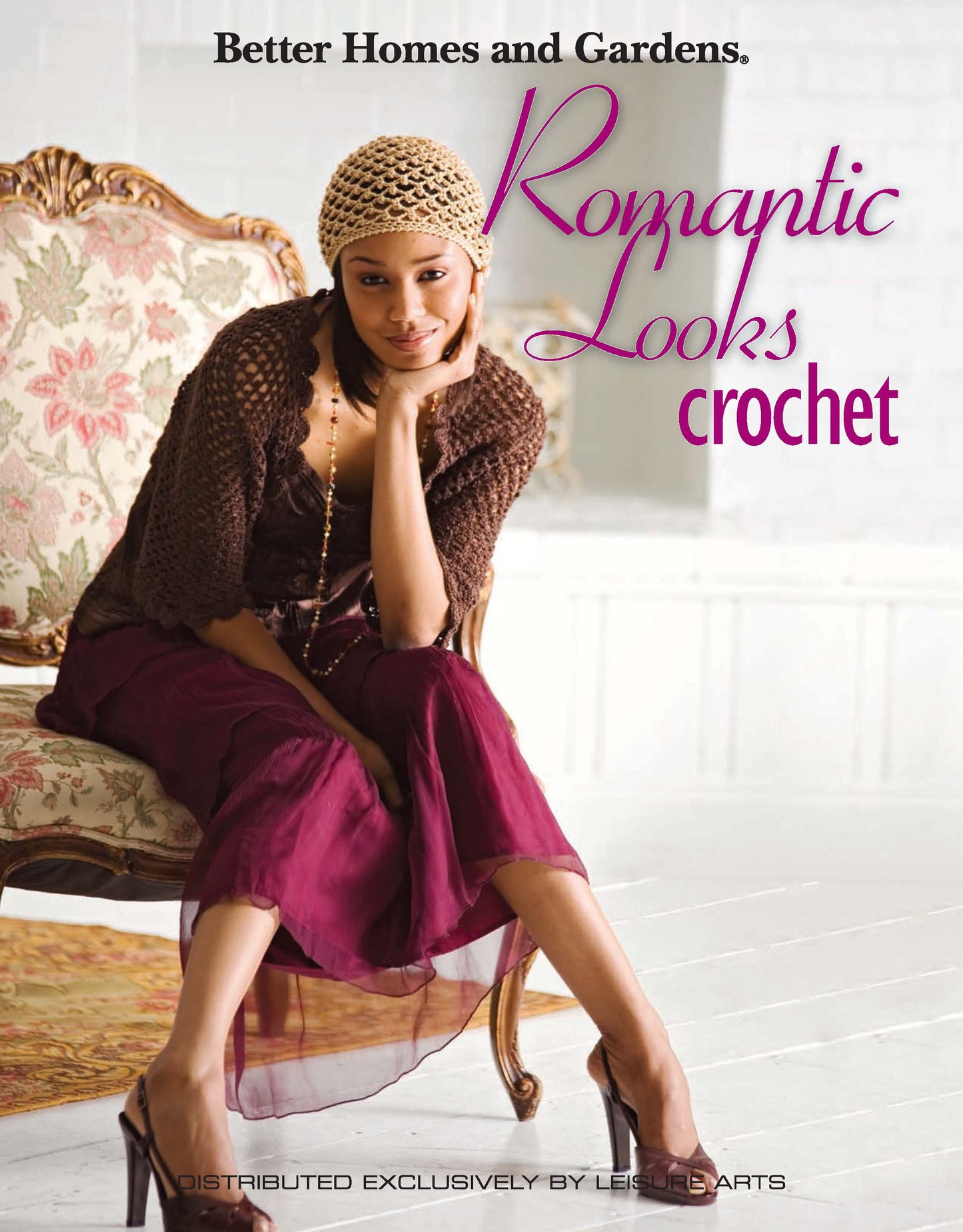 A woman in a crocheted hat, brown cardigan, and burgundy skirt sits on an ornate chair. The text reads, Romantic Looks Crochet by Leisure Arts. 48 pages in color; print ISBN available. Bright setting with white background.