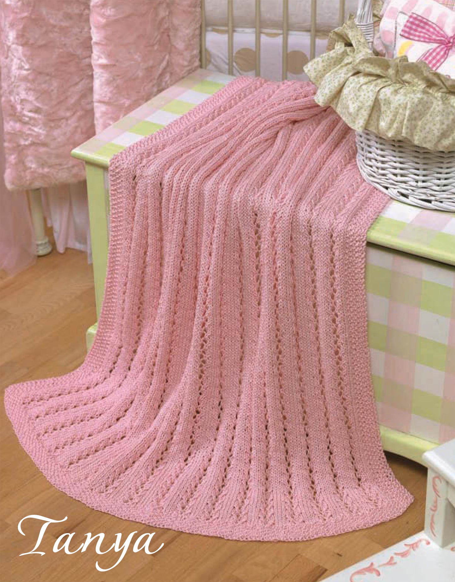A soft pink lacy baby blanket made using a beginner pattern from "Quick Knit Keepsakes, Book 2" by Leisure Arts is draped over a pastel green chest next to a white basket and crib. The name Tanya appears in cursive at the bottom left.