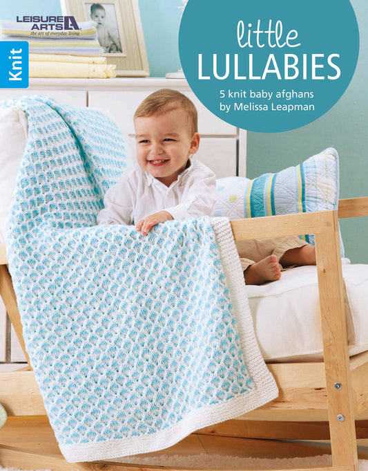 A smiling toddler sits on a wooden chair draped with a colorful knit blanket. The text reads "Little Lullabies—Easy Blankets with Beautiful Color Patterns!" by Leisure Arts. A pillow and yarn are nearby.