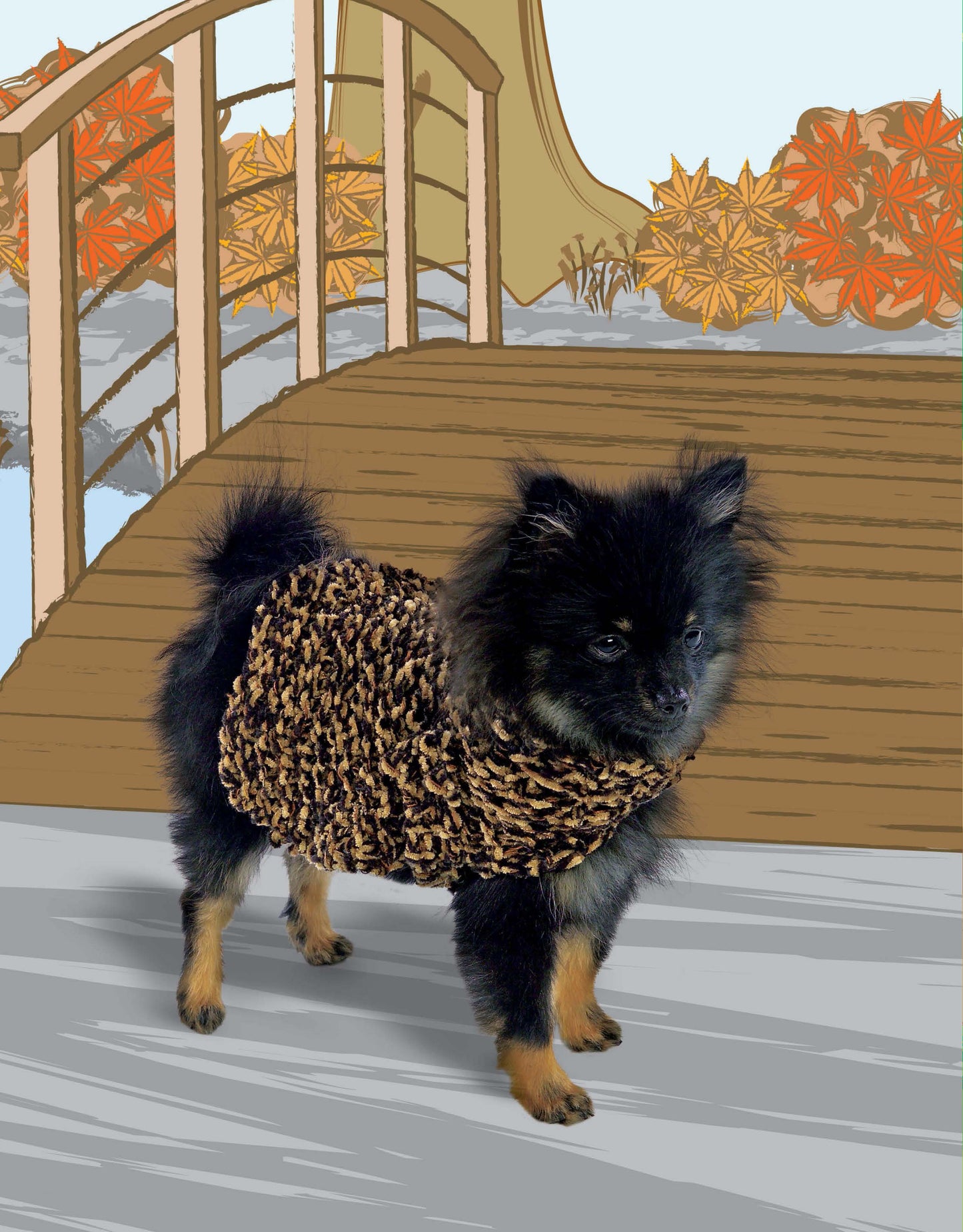 A small black and tan dog models a chunky sweater from Leisure Arts’ "Oodles of Outerwear for Canines" while standing on a wooden path by a curved bridge amid autumn trees.