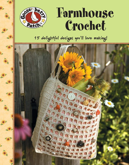 A crocheted tote with buttons and sunflowers rests on a wooden fence. The Gooseberry Patch Farmhouse Crochet Digital Download by Leisure Arts features 15 beginner-friendly crochet patterns for creative inspiration.