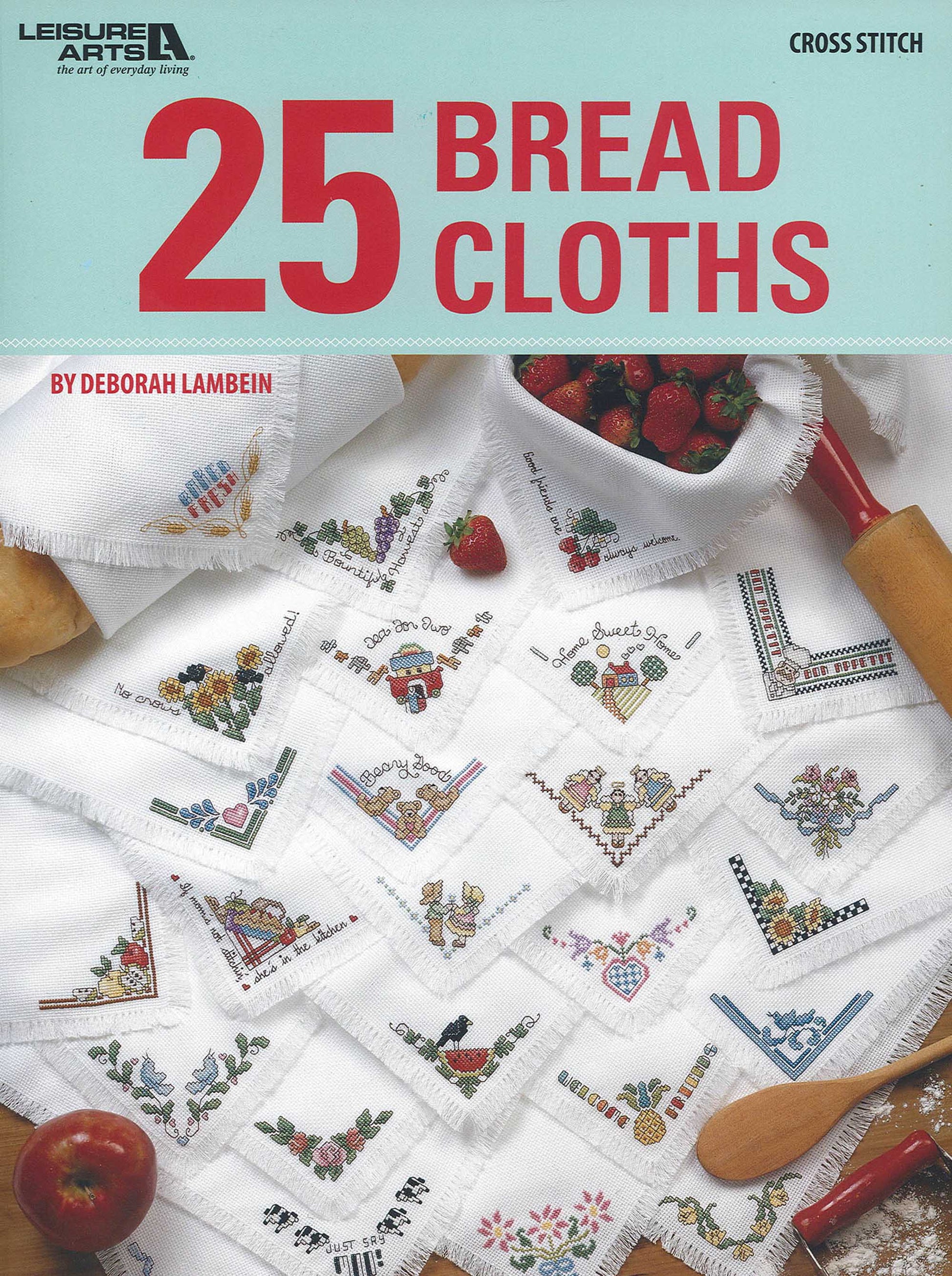 Cover of the Leisure Arts book "25 Bread Cloths," showcasing embroidered white cloths with colorful designs and charming corner decorations, surrounded by baking items and a bowl of strawberries.