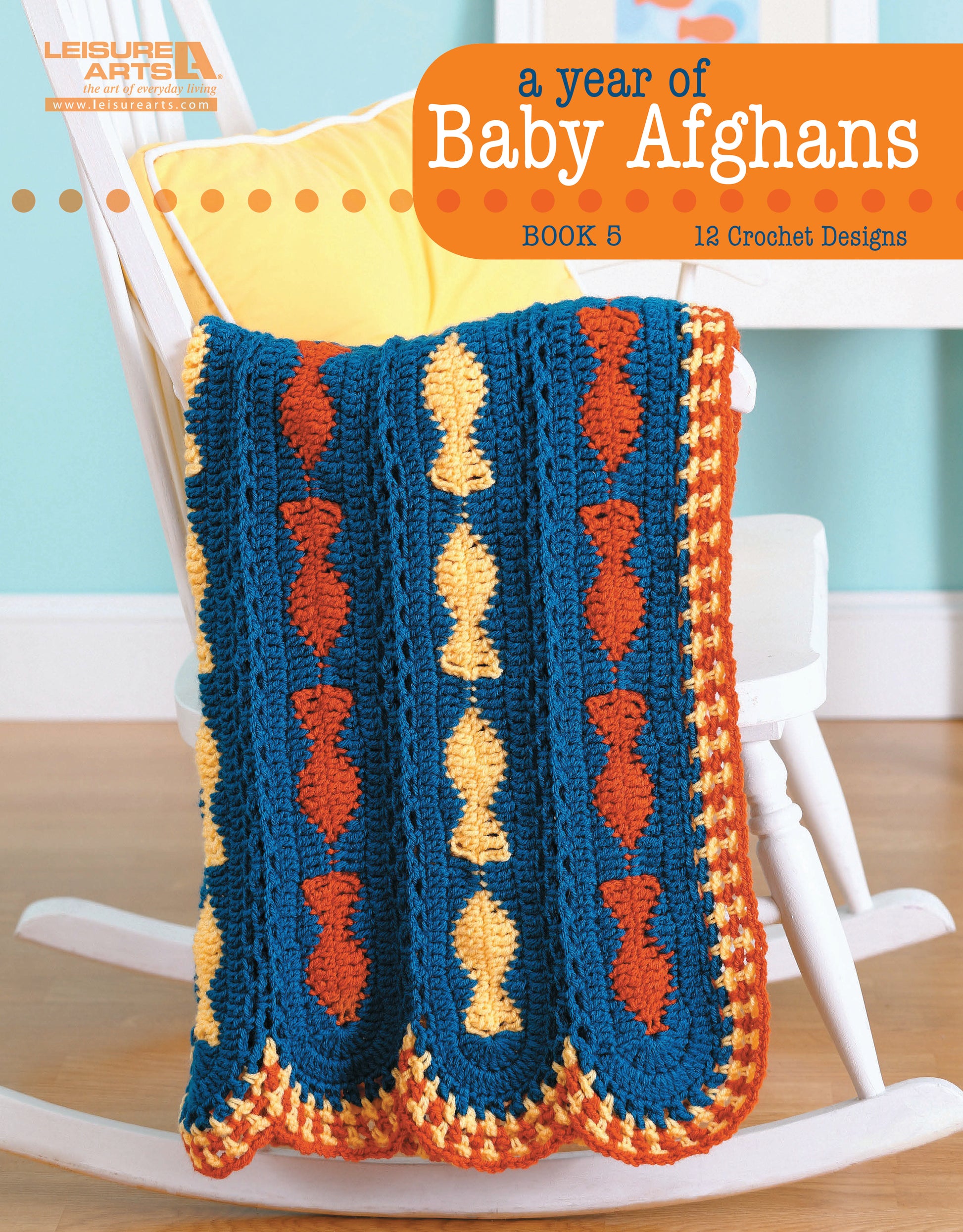 A vibrant crocheted baby afghan with blue, orange, and yellow fish is draped over a white rocking chair, highlighting one of many cozy patterns from “A Year of Baby Afghans, Book 5” by Leisure Arts.