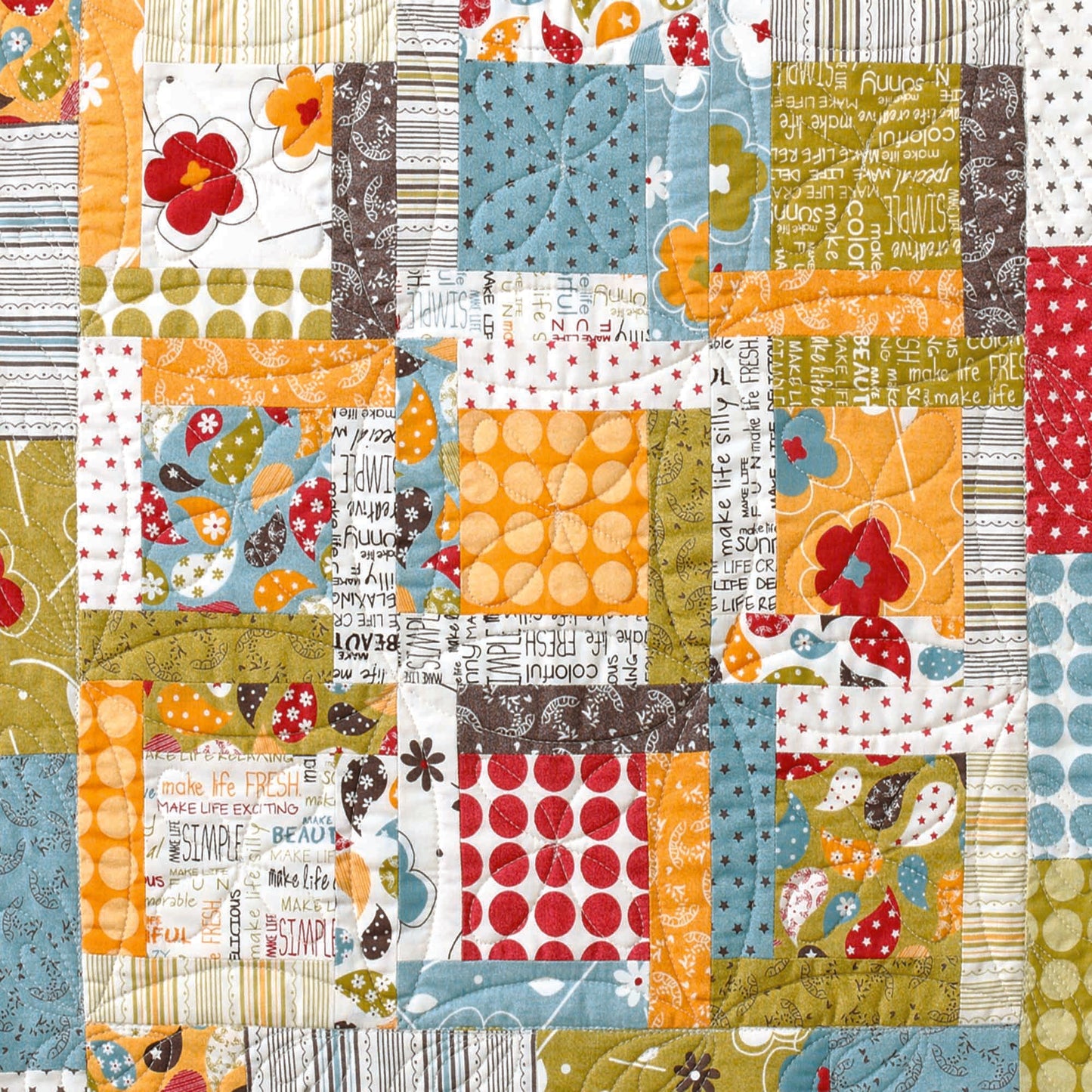 The Leisure Arts Three Times the Charm Quilt Projects Digital Download features a colorful patchwork of squares and rectangles in polka dots, flowers, stripes, text, and leaves—perfect for baby showers or easy quilting in orange, yellow, blue, green, red, and white.