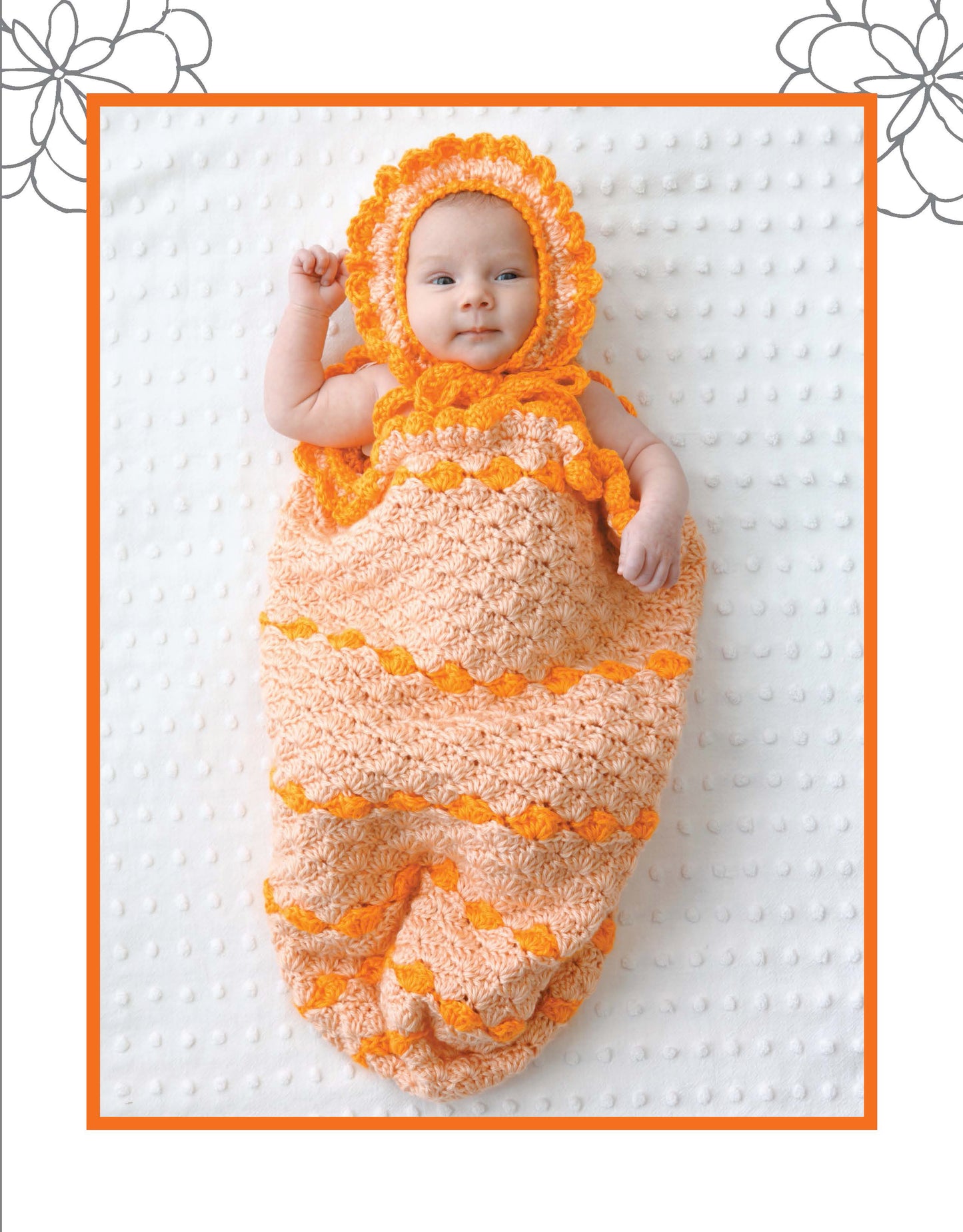 A baby smiles on a white textured blanket, wrapped in a peach and orange Crochet Dreamy Cocoon with matching bonnet by Leisure Arts—showcasing the charm of adorable baby crochet patterns.