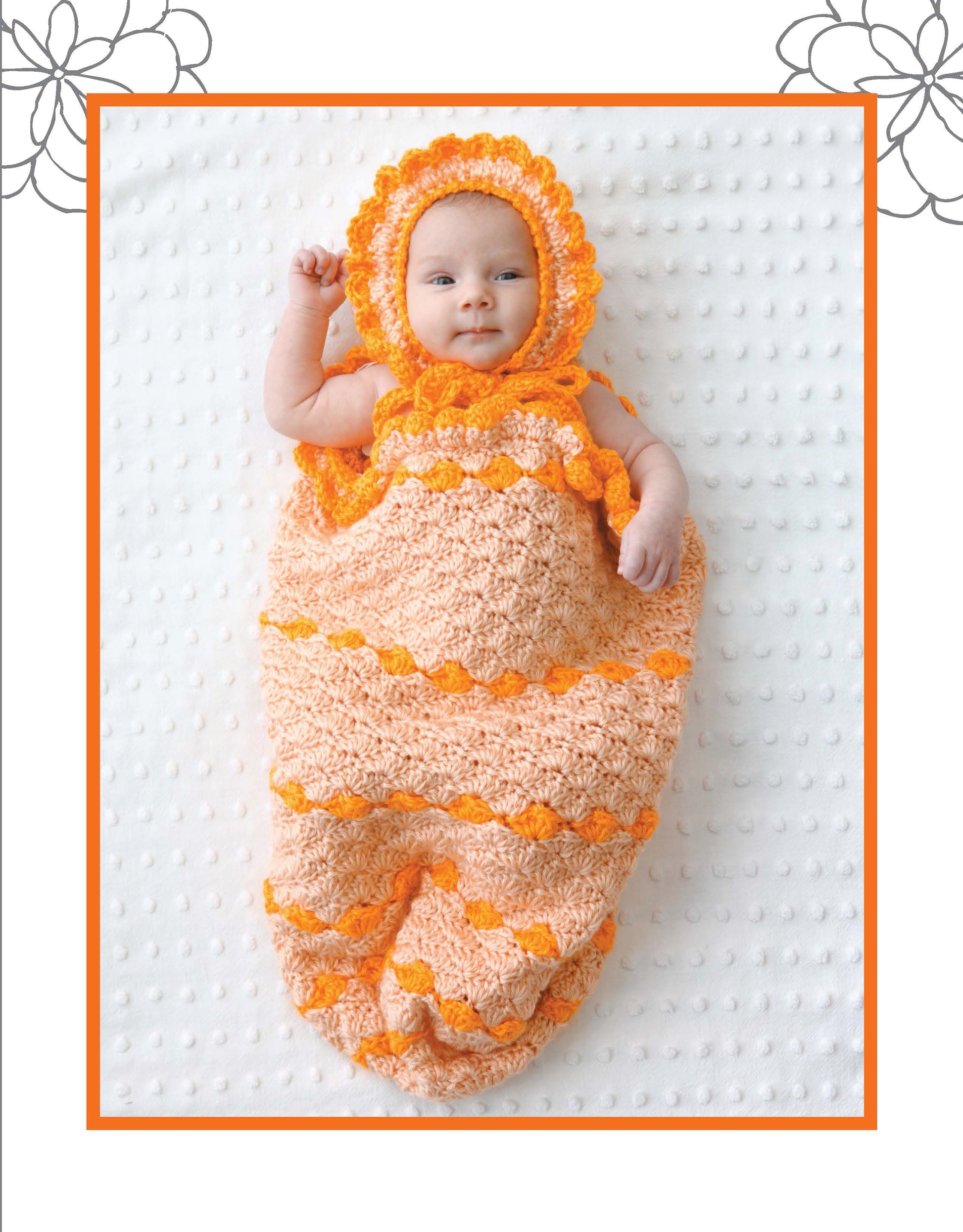 A baby smiles on a white textured blanket, wrapped in a peach and orange Crochet Dreamy Cocoon with matching bonnet by Leisure Arts—showcasing the charm of adorable baby crochet patterns.