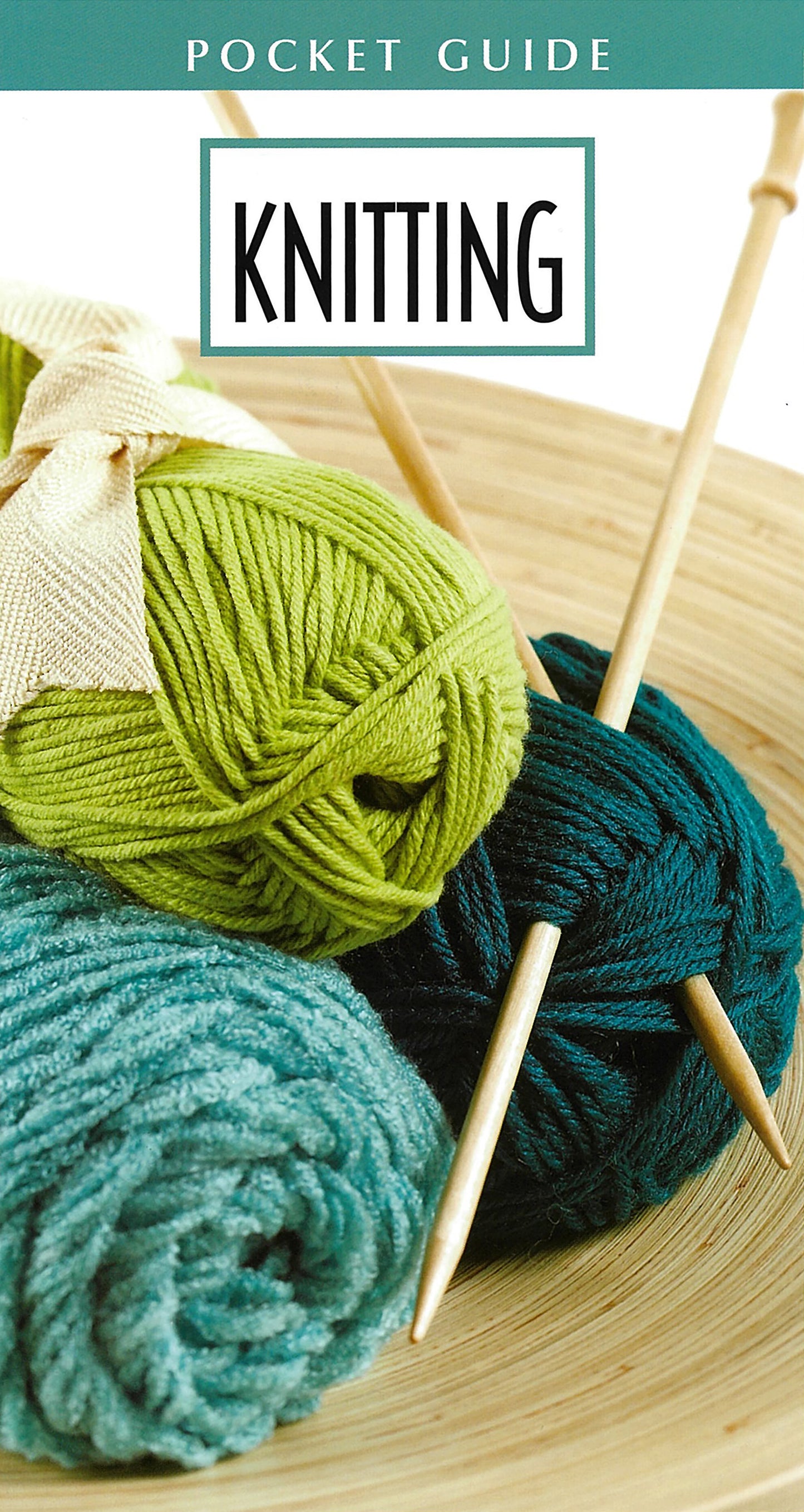 Three balls of green, teal, and light blue yarn with wooden knitting needles rest in a bowl beside the Knitting Pocket Guide by Leisure Arts—a must-have for beginners. Includes print ISBN for easy reference.