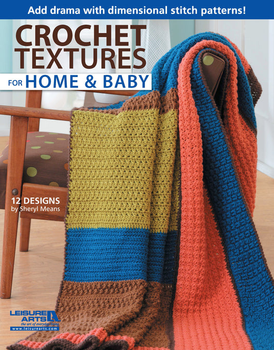 A vibrant crocheted sampler afghan in blue, orange, mustard, and brown covers a chair. The cover features “Crochet Textures for Home & Baby—12 Designs by Sheryl Means” from Leisure Arts.
