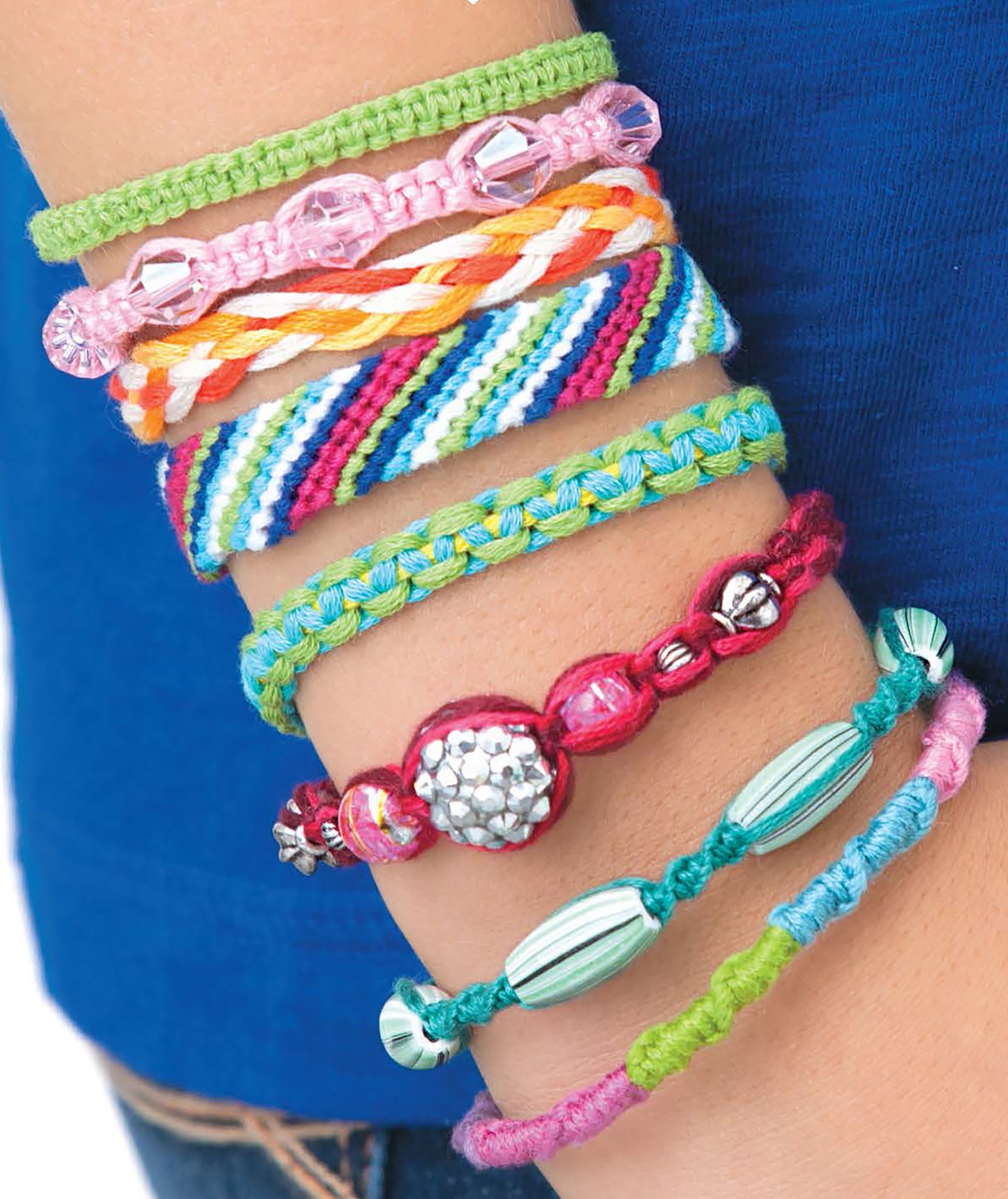 A close-up shows a wrist adorned with colorful, braided and beaded bracelets, set against a blue shirt—ideal inspiration for crafters or kids exploring the "Friendship Bracelets Digital Download" from Leisure Arts.
