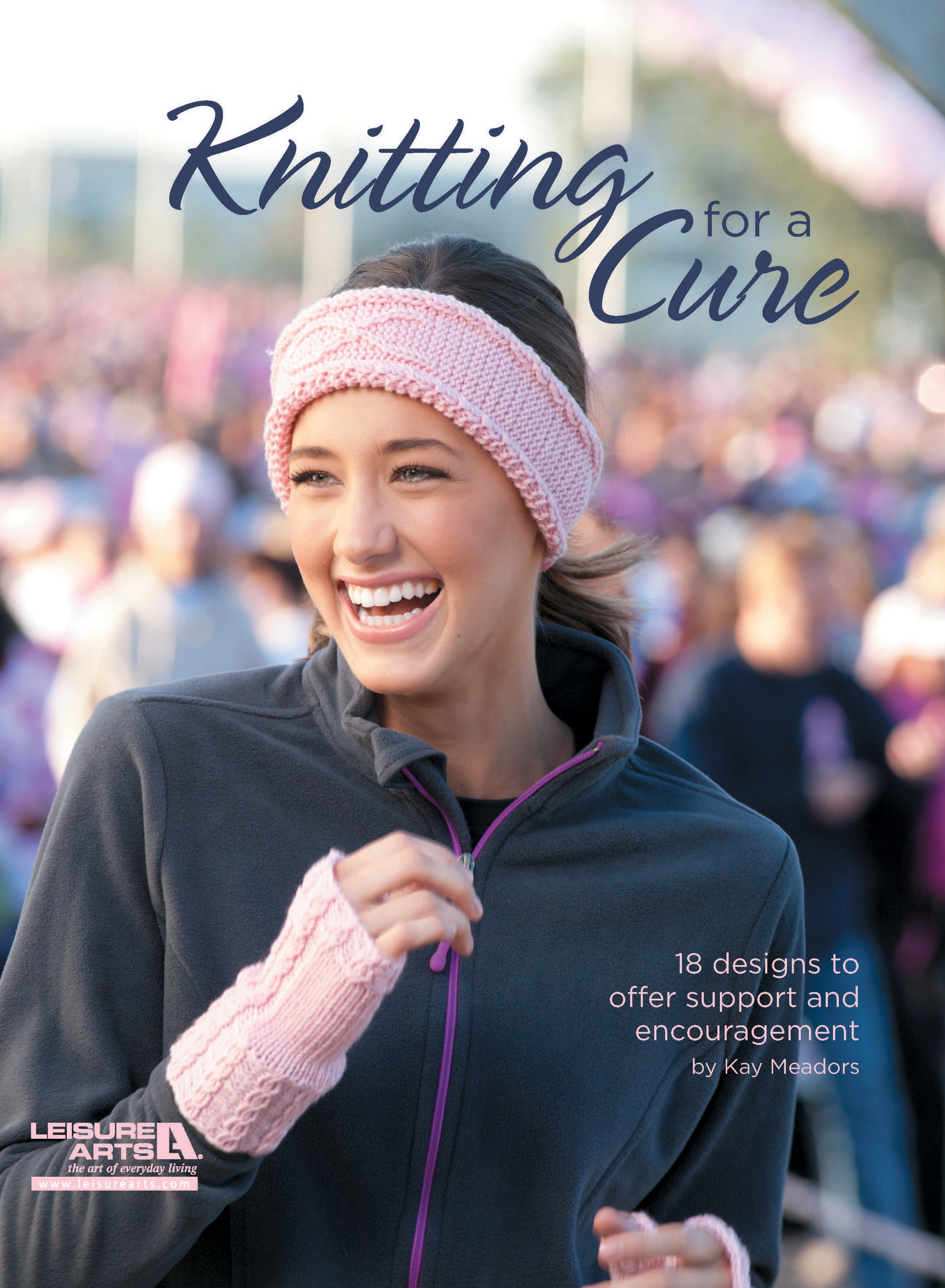 A young woman in a pink knitted headband and fingerless gloves smiles at an outdoor event. Text: Knitting for a Cure by Leisure Arts—18 knitting patterns to inspire support and encouragement.