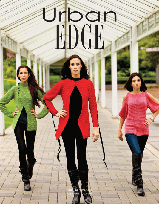 Three women walk confidently under a white outdoor pavilion in vibrant green, red, and pink cardigans from Leisure Arts’ Crochet Urban Edge Fashion collection, styled with black pants and boots. The text "Urban EDGE" appears at the top.