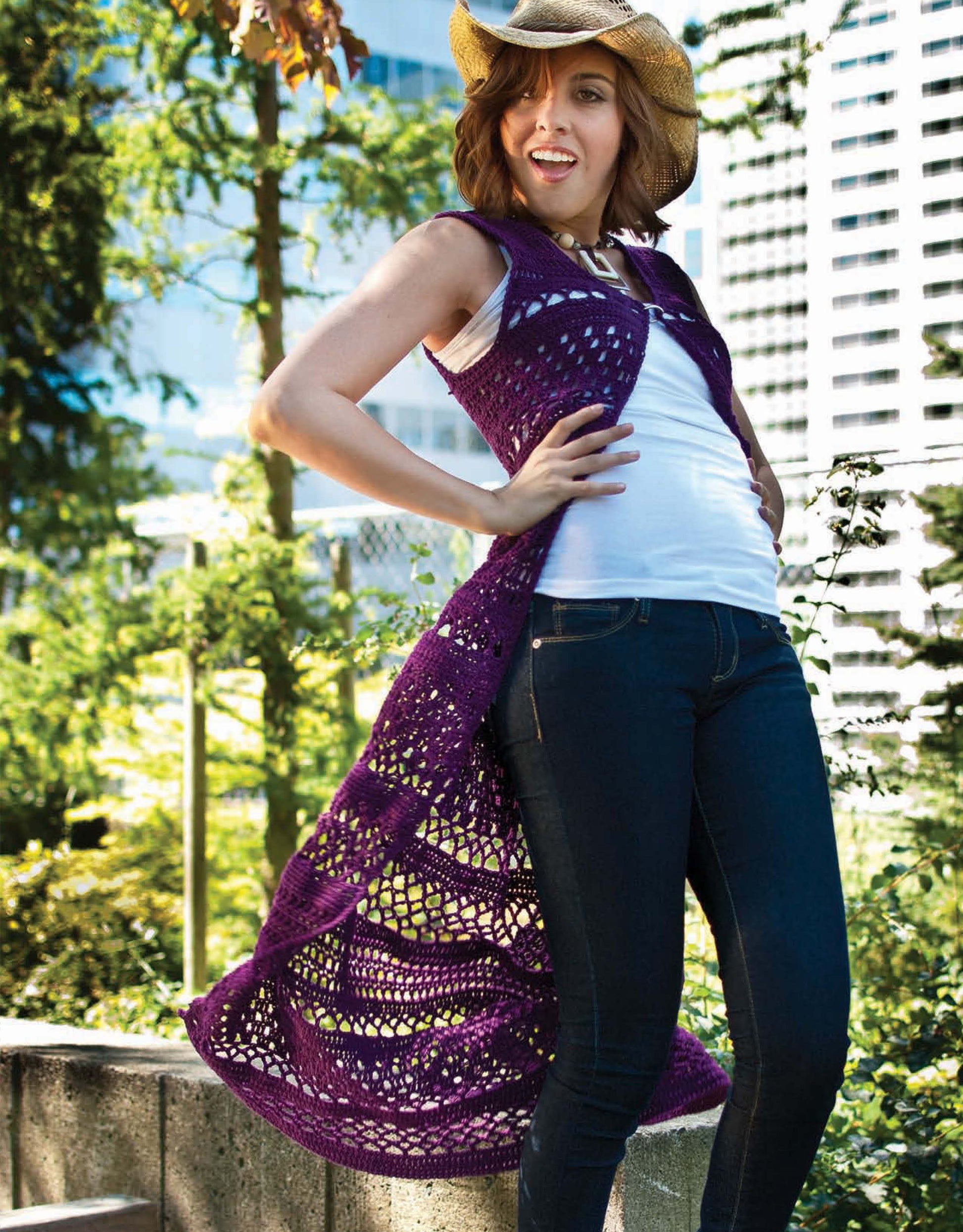 A woman in a cowboy hat, white top, and jeans models Leisure Arts’ Crochet Urban Edge Fashion—a stylish choice for those seeking trendy women’s crochet clothing and unique crochet garment patterns.