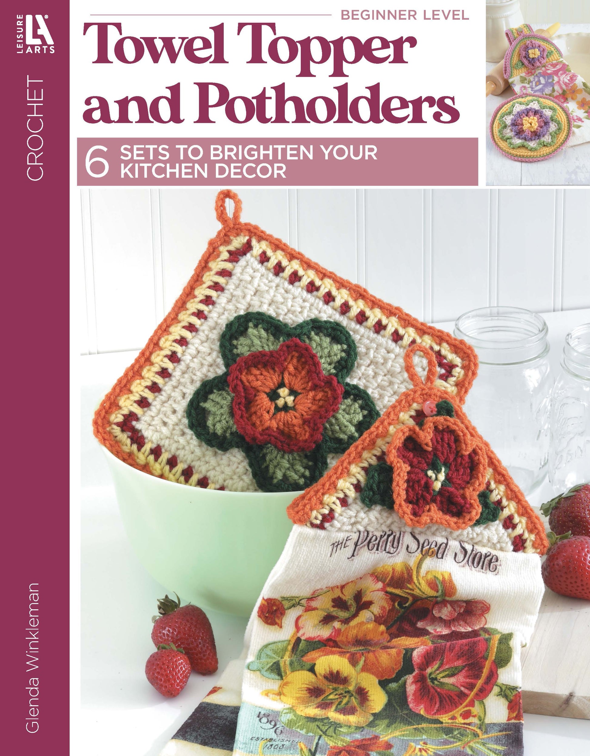 Cover of Leisure Arts’ "Towel Toppers and Potholders Digital Download": colorful crochet pot holders hang above a strawberry-themed kitchen towel—perfect for adding charm to your kitchen or gifting. Fresh strawberries and jars displayed in the background.