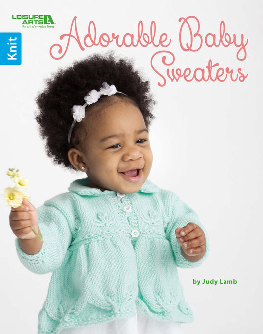 Cover of Adorable Baby Sweaters Digital Download by Leisure Arts. A smiling baby in a mint green knit cardigan and floral headband holds a flower—ideal for anyone seeking easy, charming knitting patterns.