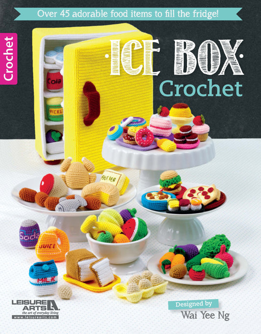 Colorful crocheted food and amigurumi toys are displayed with a yellow crocheted fridge in the background. This image serves as the cover for "Ice Box Crochet" by Leisure Arts.