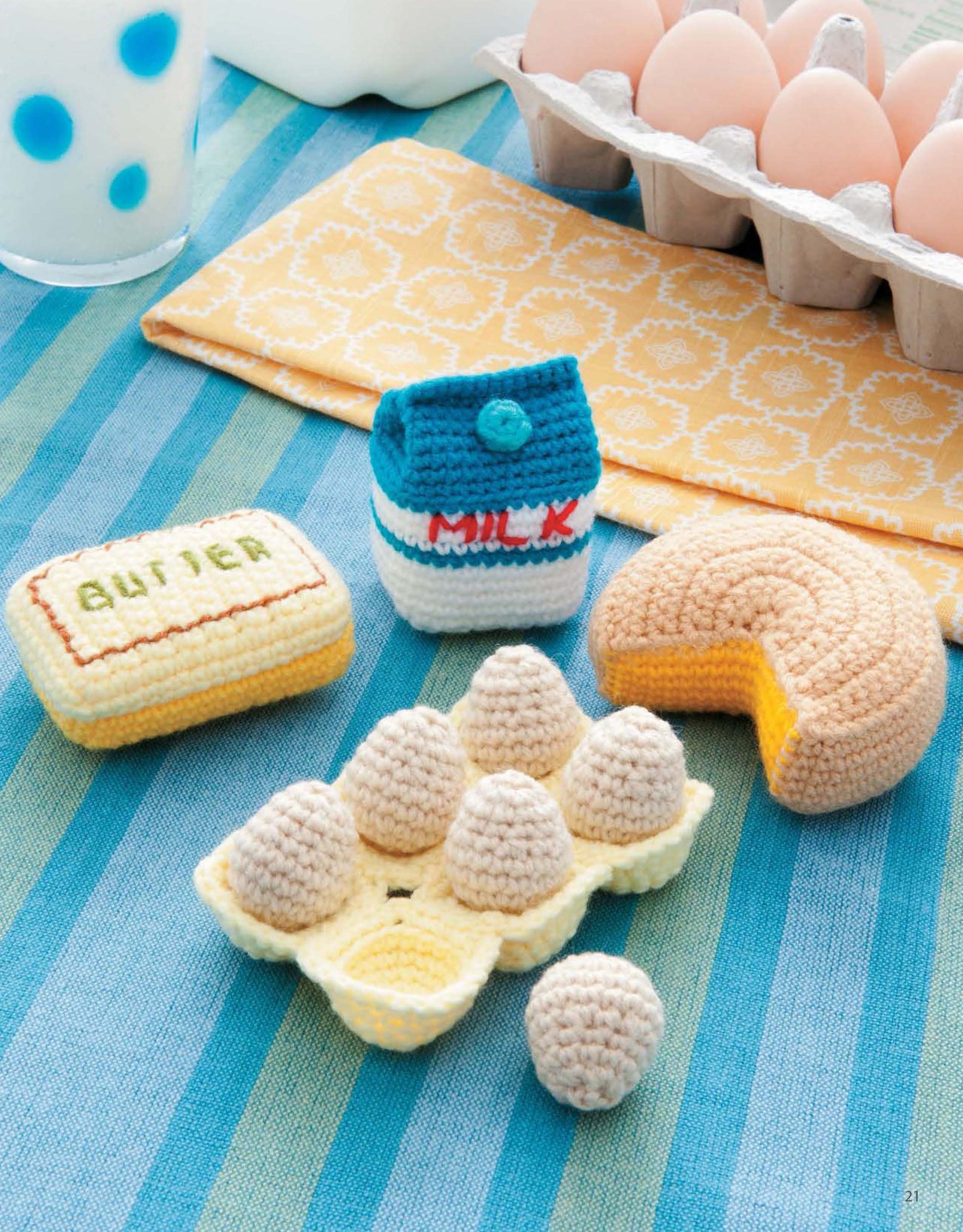 Ice Box Crochet by Leisure Arts features crocheted food items: a milk carton, butter, eggs (with one out), and cake slice, displayed on a striped blue tablecloth with real eggs in the background.