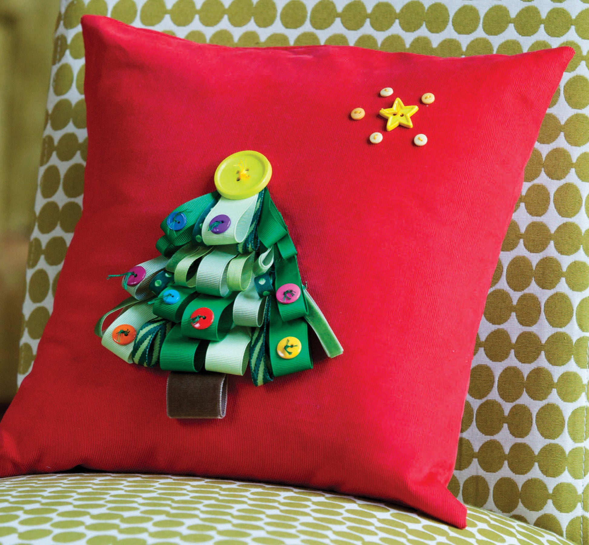 Add festive cheer to your home with "Crafting with Buttons and Ribbons" by Leisure Arts—a red pillow featuring a handmade Christmas tree from green ribbon loops, colorful buttons, beaded accents, and a star as the topper.