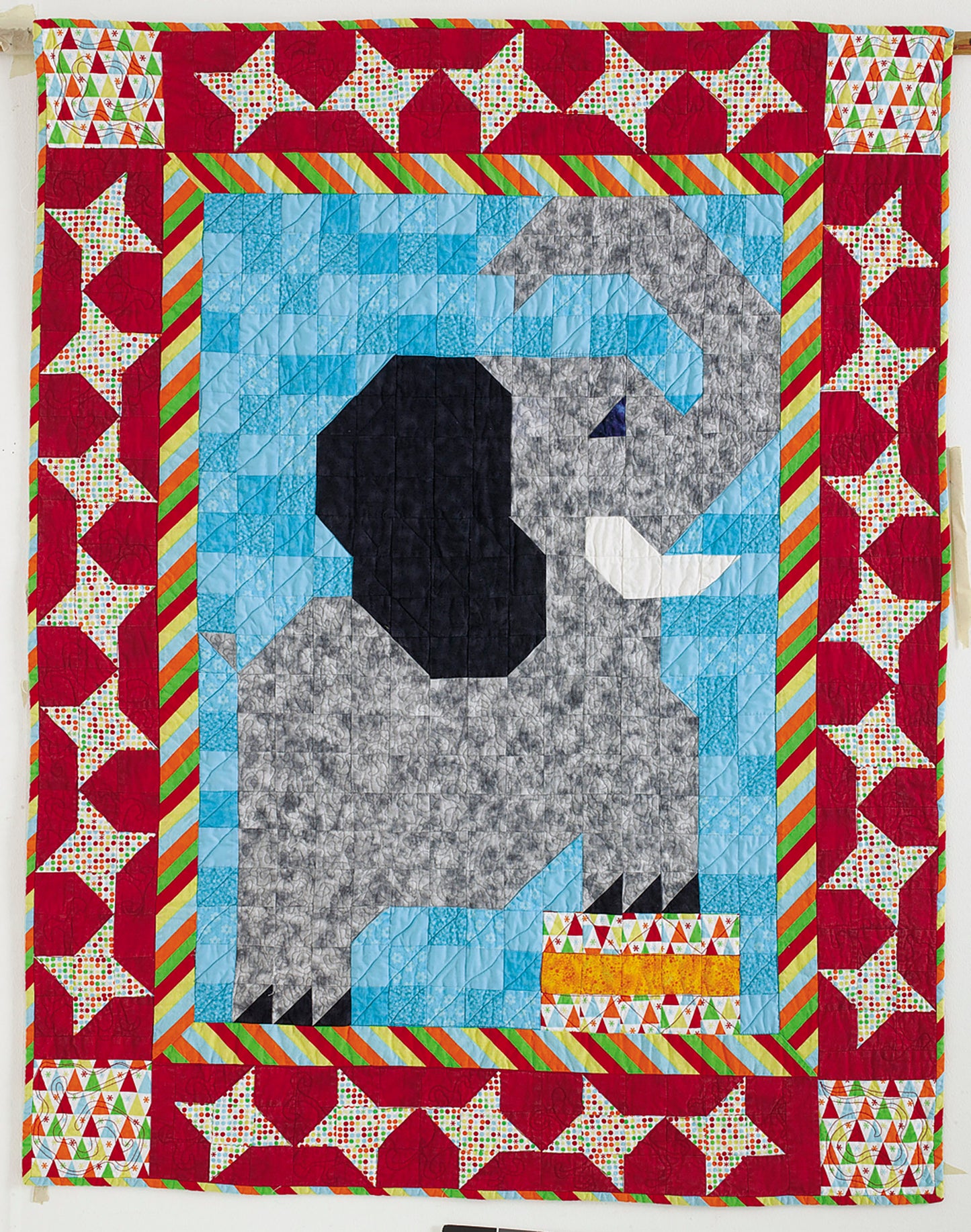 The Leisure Arts Patch Pals Collection—Best of Quiltmaker! features a beginner-friendly quilt with a geometric gray elephant on blue, bordered by red, green, and patchwork squares in vibrant patterns.