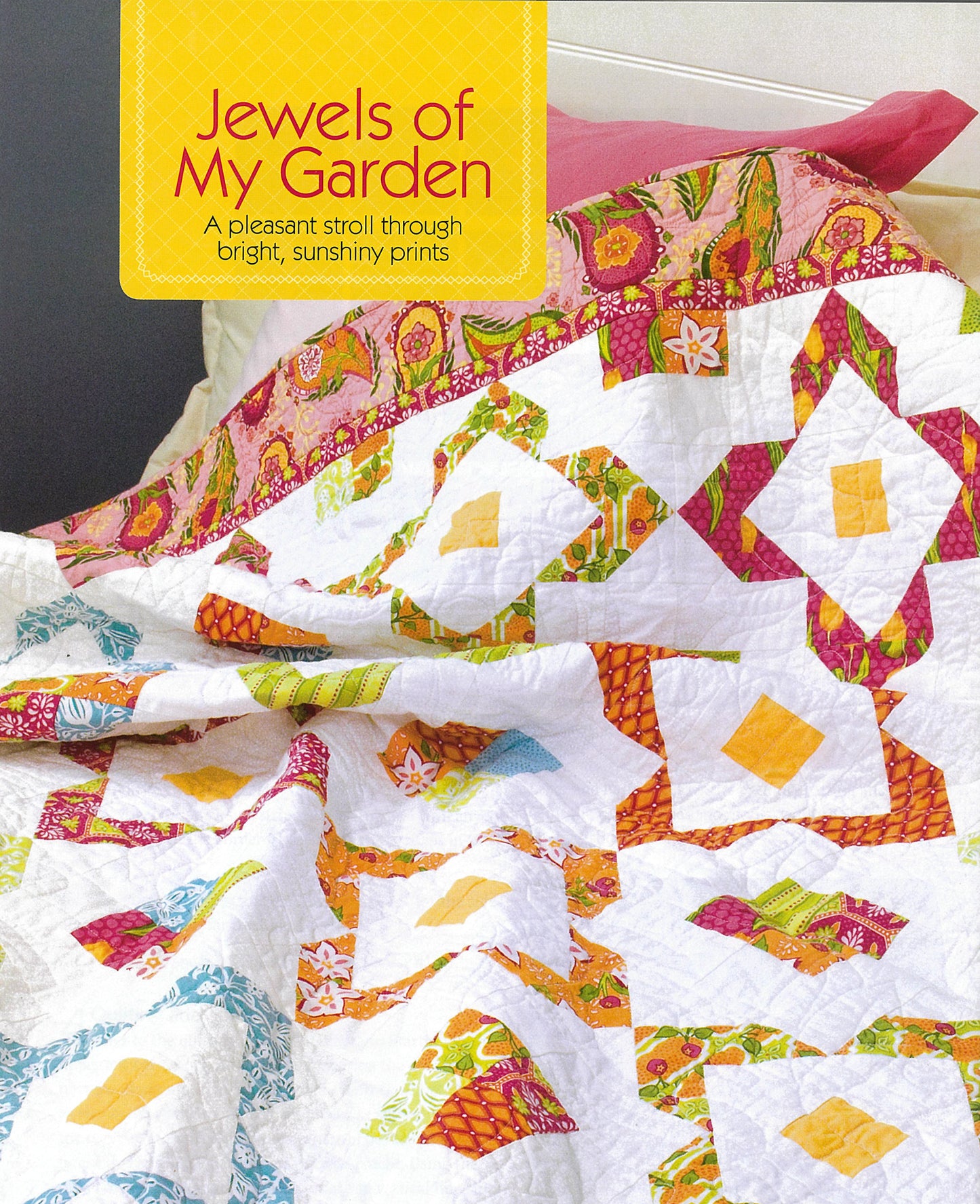 A vibrant quilt with diamond and square patterns in yellow, orange, green, blue, and pink rests on a bed. A sign features "Simple Patchwork Quilts—Best of Quiltmaker" from Leisure Arts, perfect for beginners using bright fabrics.