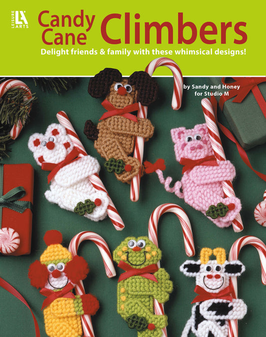 The cover of Leisure Arts' "Candy Cane Climbers" shows six crocheted animals hugging candy canes among Christmas gifts and greenery. Enjoy whimsical animal ornament patterns and festive holiday crafts!.