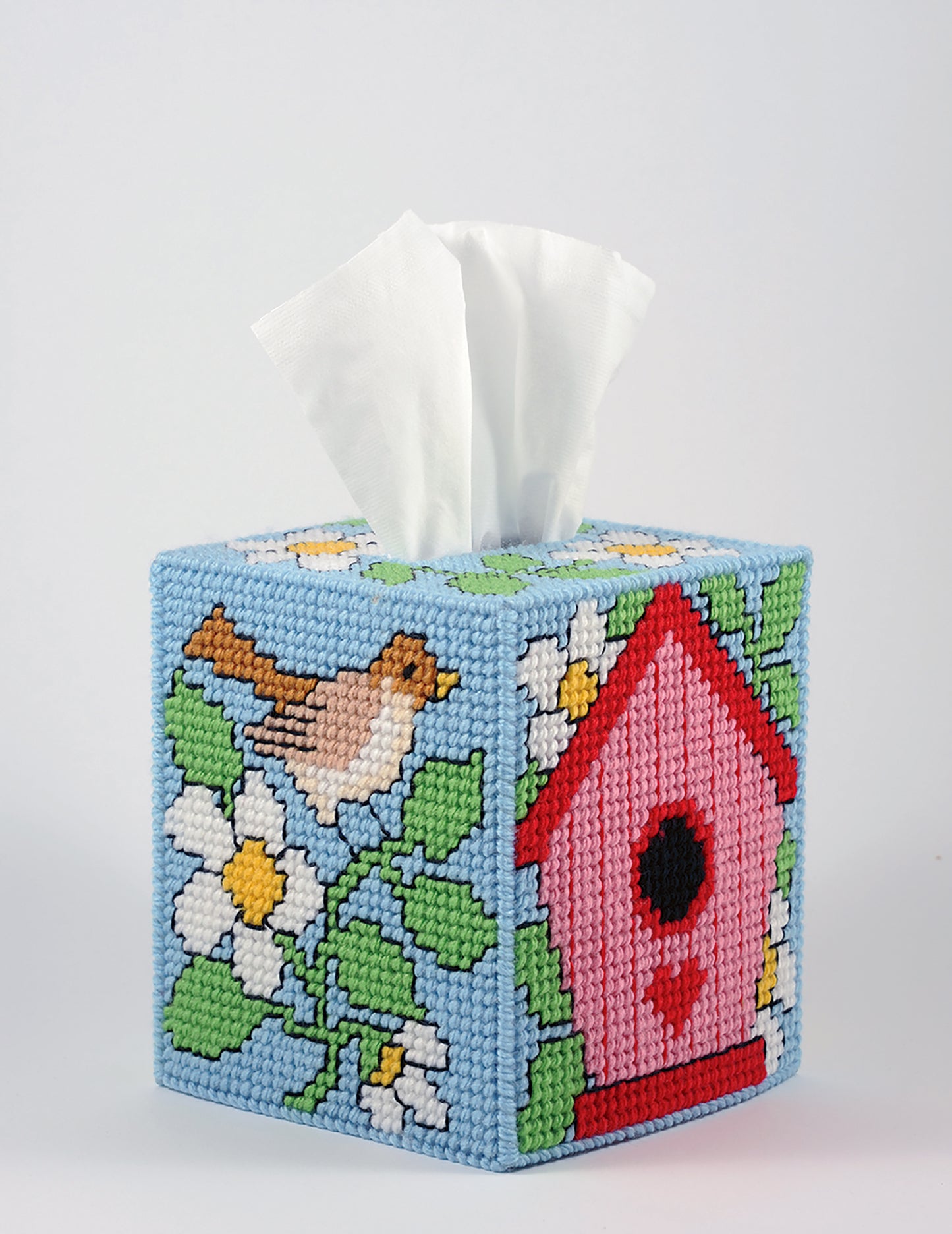Brighten any room with Leisure Arts’ "Tissue Box Covers—8 Projects," including designs like a brown bird, white flowers, green leaves, and a pink birdhouse on light blue. Tissues dispense from the top for added charm.